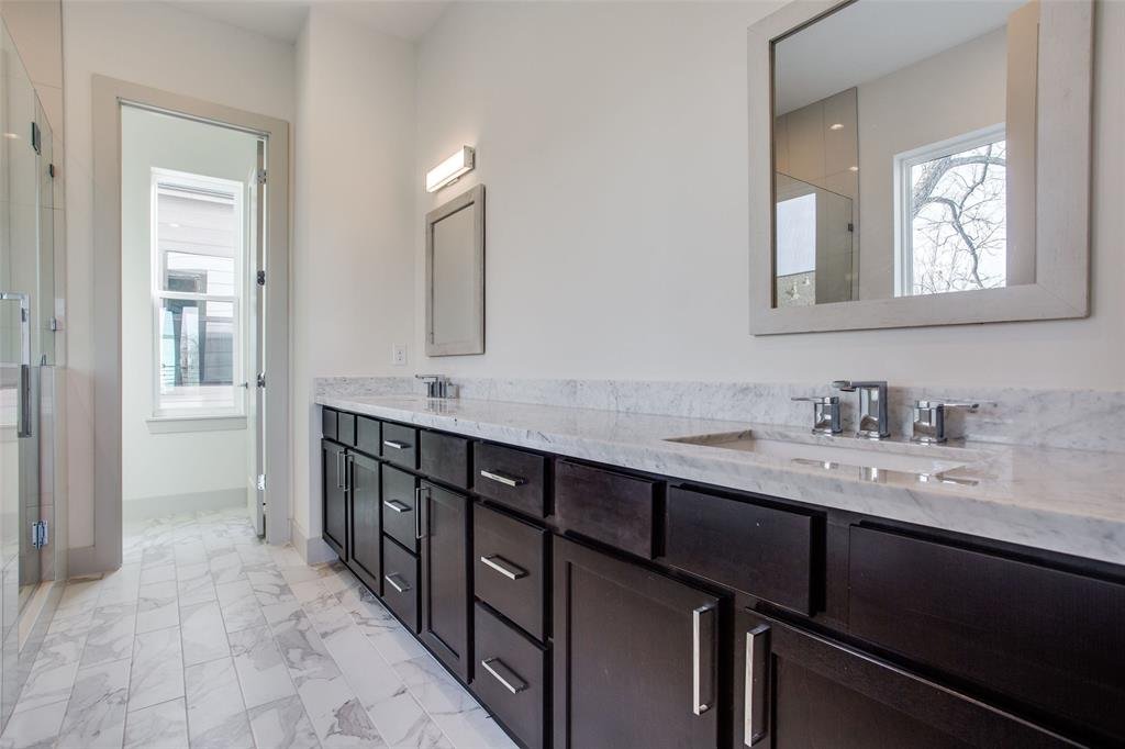 Modern bathroom with black cabinetry, white marble countertops, and a large mirror above the sinks.