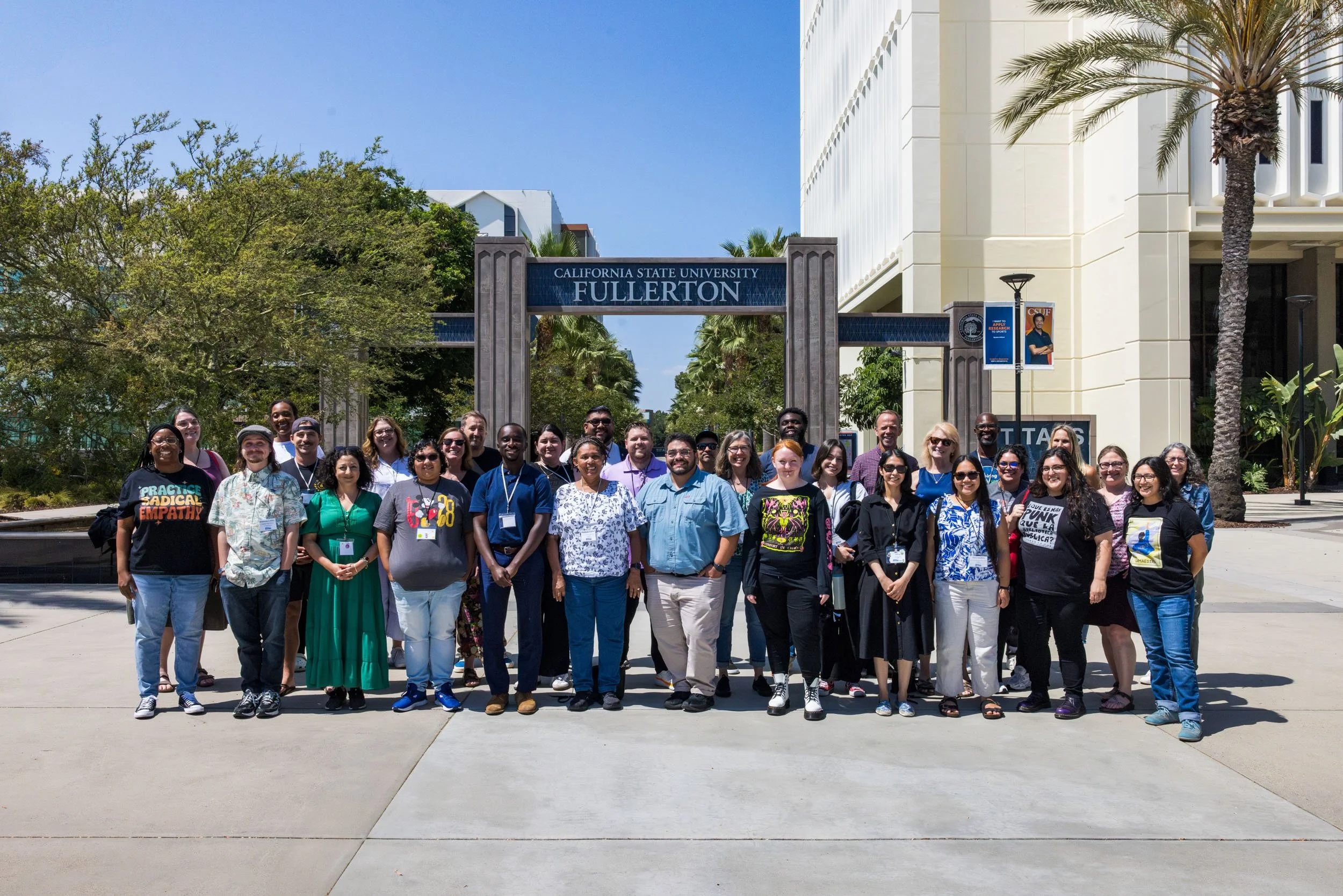 Group of diverse students and faculty standing in front of California State University Fullerton entrance on a sunny day.