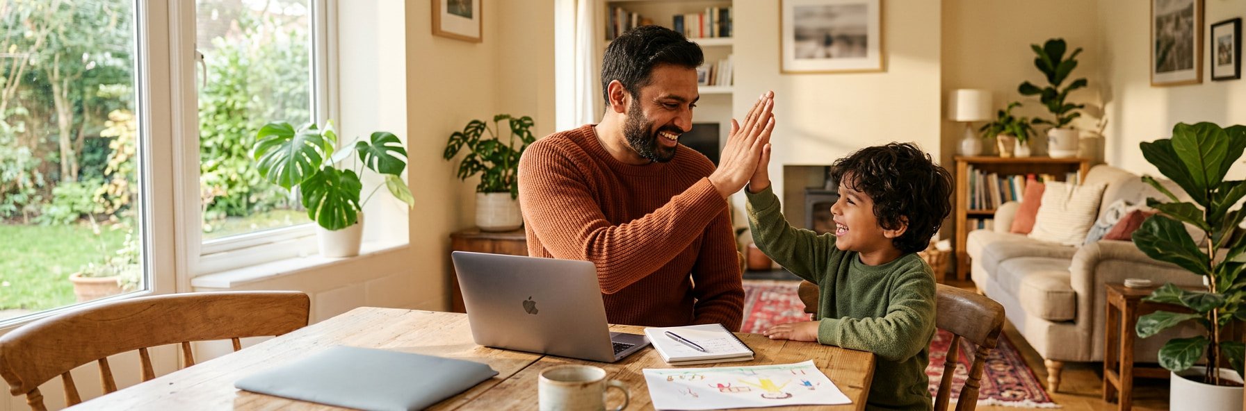 Father and young son sharing a high five at the kitchen table after a telehealth speech therapy session