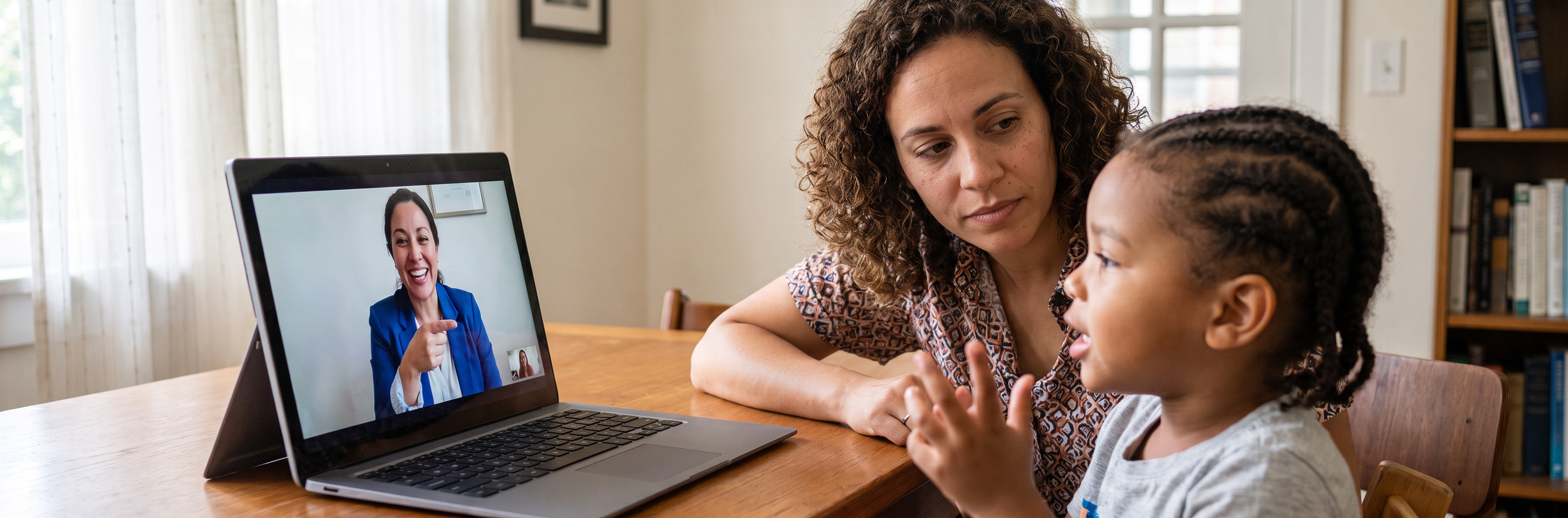Mother and child consulting with speech therapist via telehealth video call on laptop