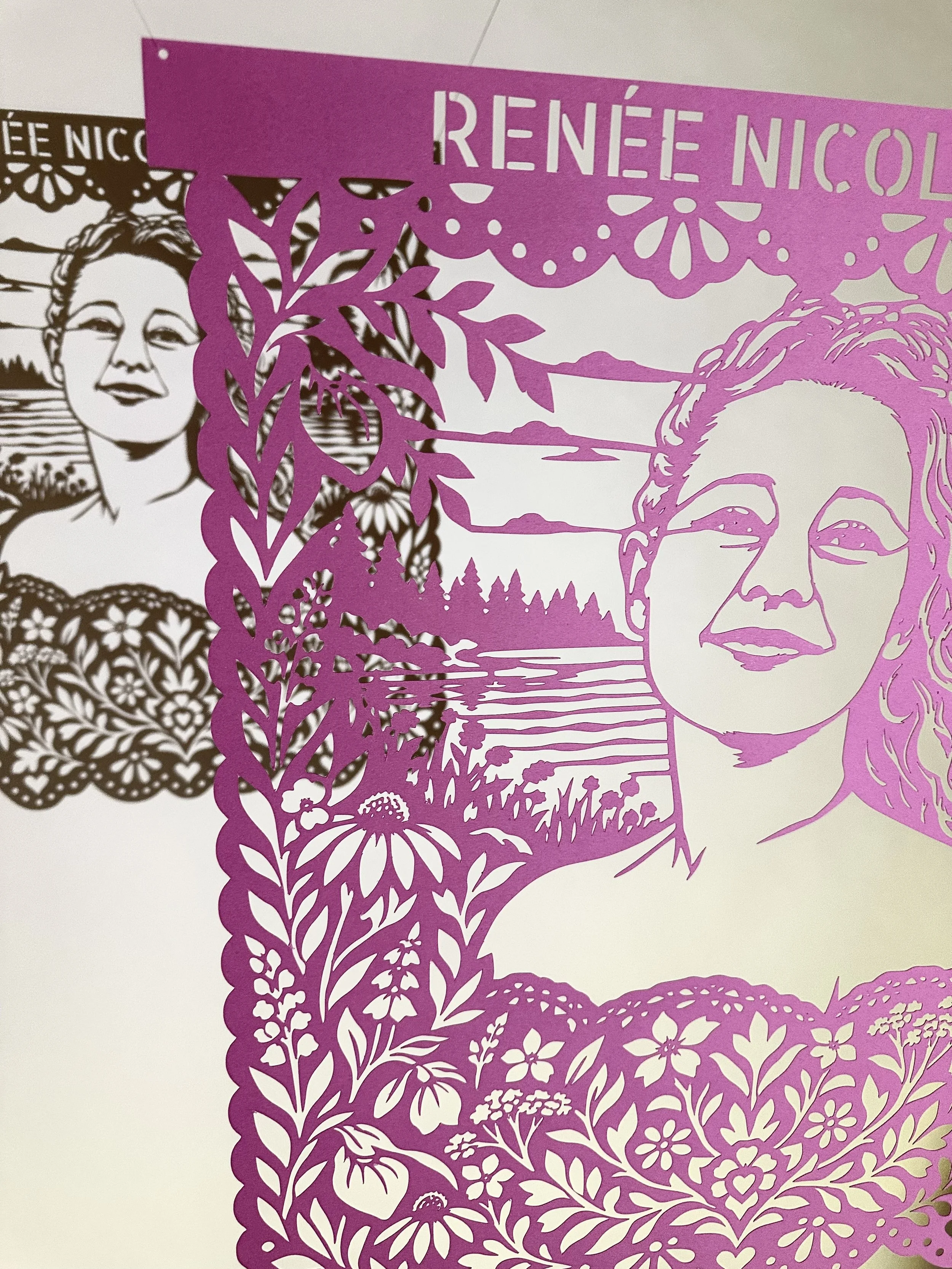 Angled view of Renee Nicole Good’s cut paper portrait showing the layered shadows of the papel picado.