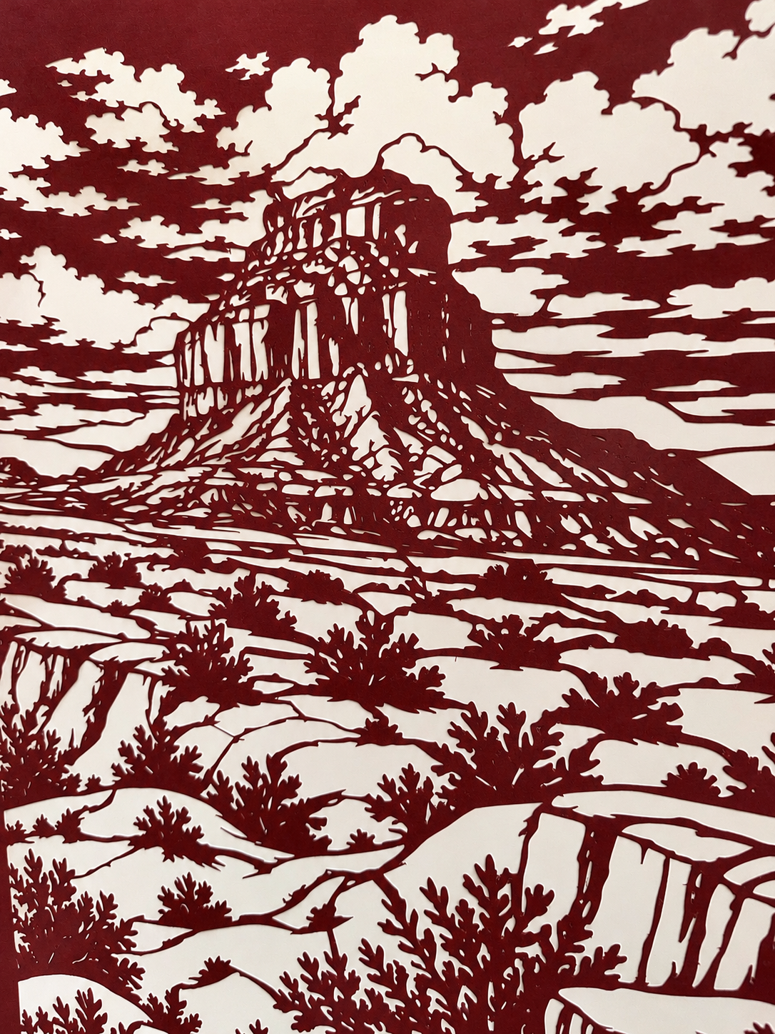 Detailed view of rock formations, layered clouds, and desert terrain in Alessandra Gutierrez's Chaco Canyon cut paper art.