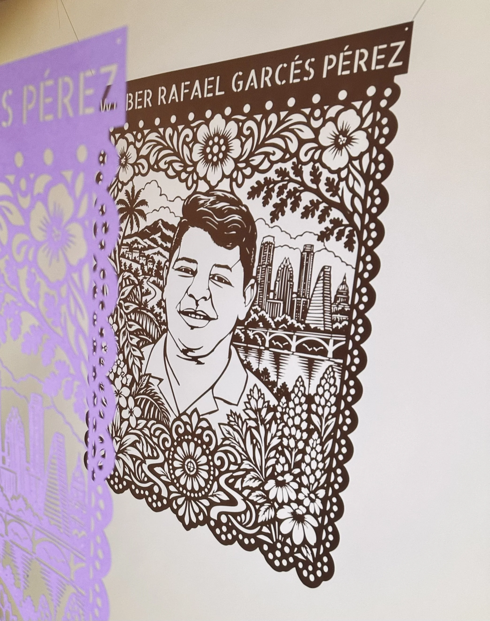 Angled view of Wilber Rafael Garcés Pérez’s Papel Memoria papel picado portrait casting a shadow on the wall.