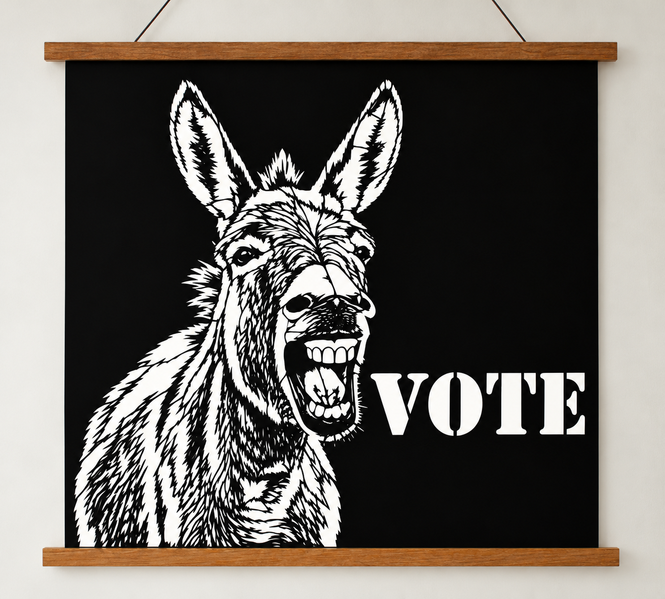 Writing       Ruthie political donkey VOTE poster, original black cut paper wall art hanging at an angle from a wooden poster hanger against a neutral studio wall.