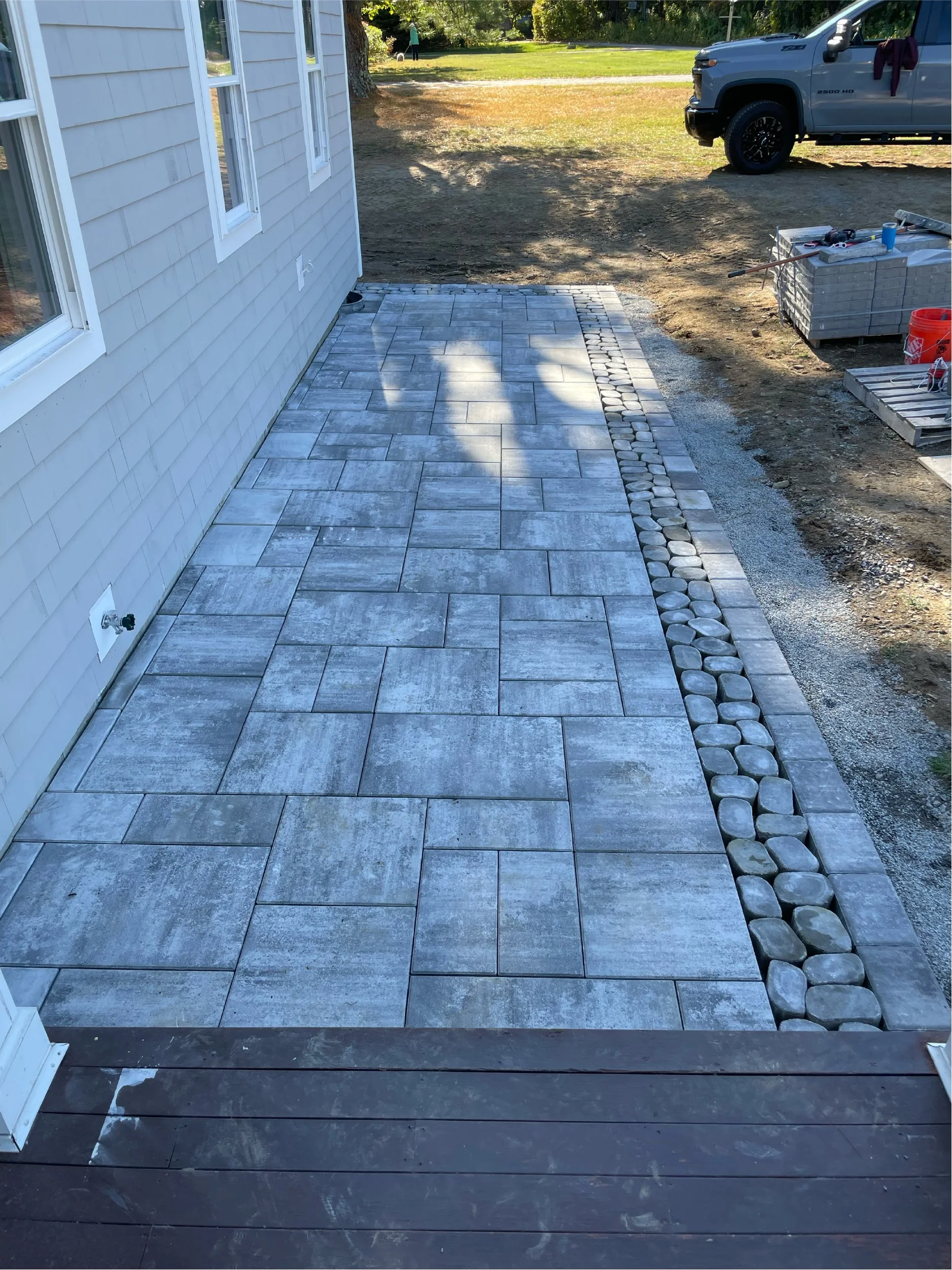 Gray limestone and river rock front patio built in Scarborough, Maine by The Englishmen Masonry