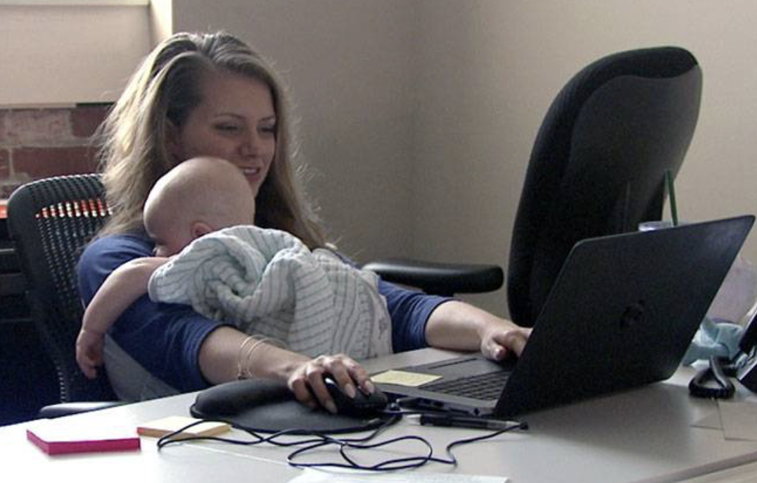 remote working parent balancing caregiving and work responsibilities with baby at desk