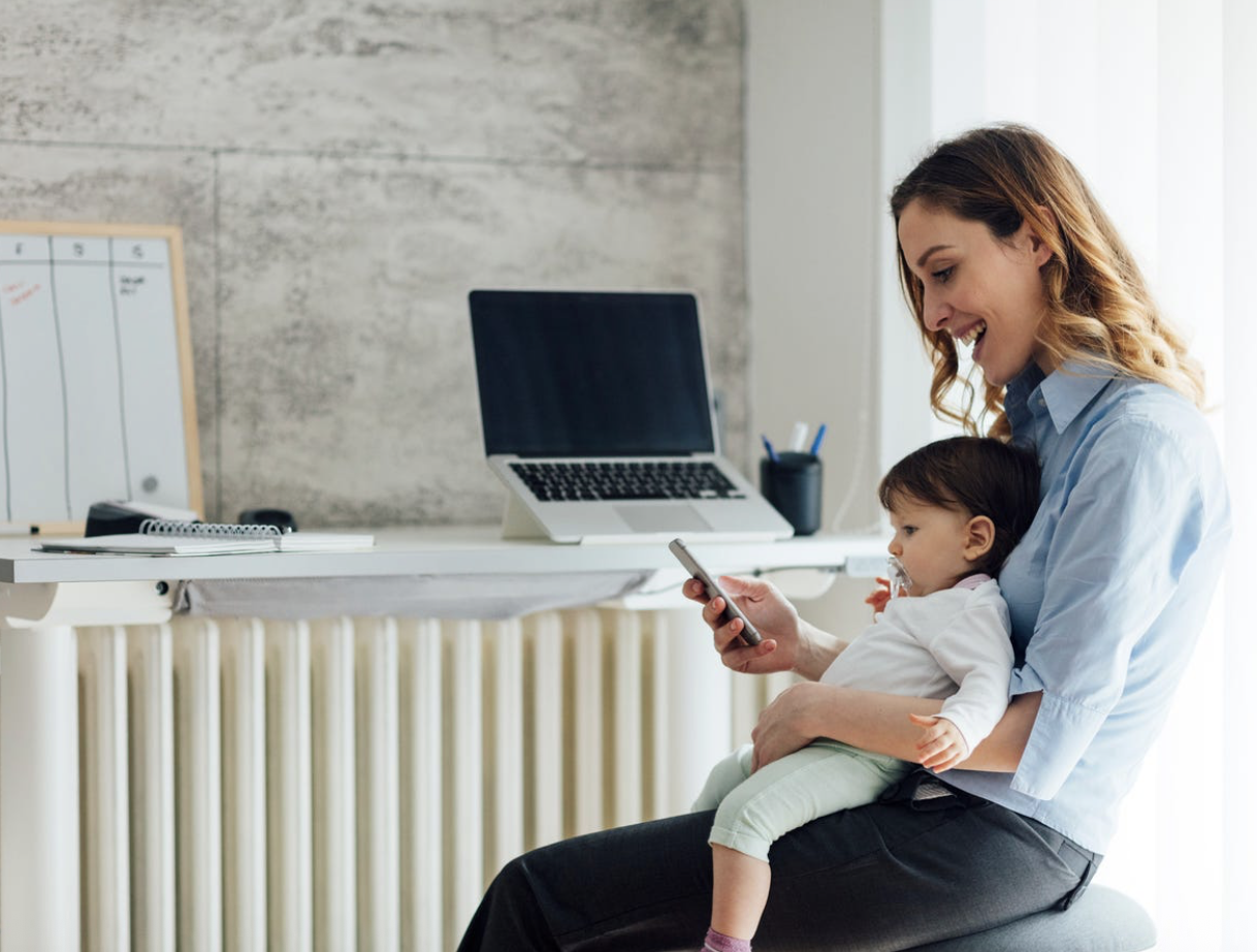 caregiver working from home while holding baby and managing flexible work schedule