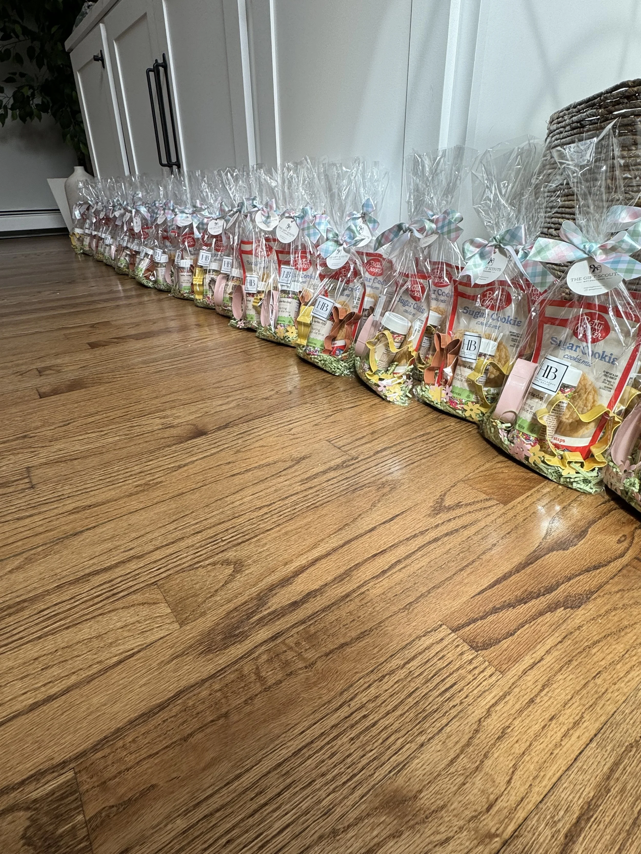 Multiple gift bags containing cookies and bunny decorations arranged on a hardwood floor.