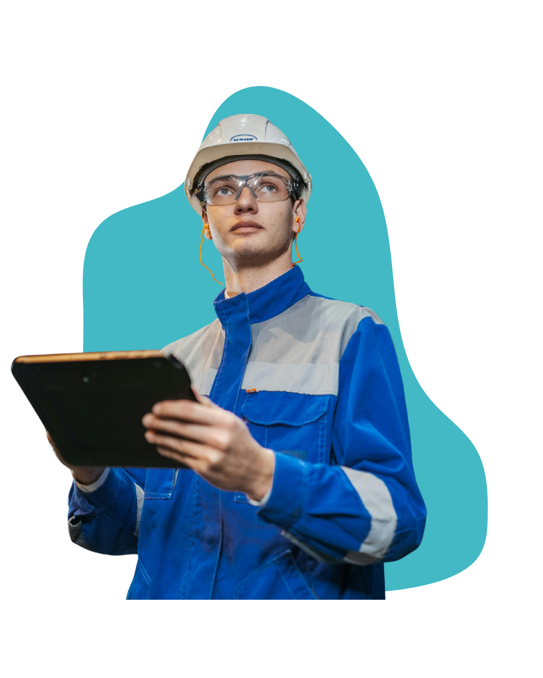 A young male engineer or technician in a blue uniform and safety helmet, holding a tablet and looking up thoughtfully, with safety glasses and earplugs.