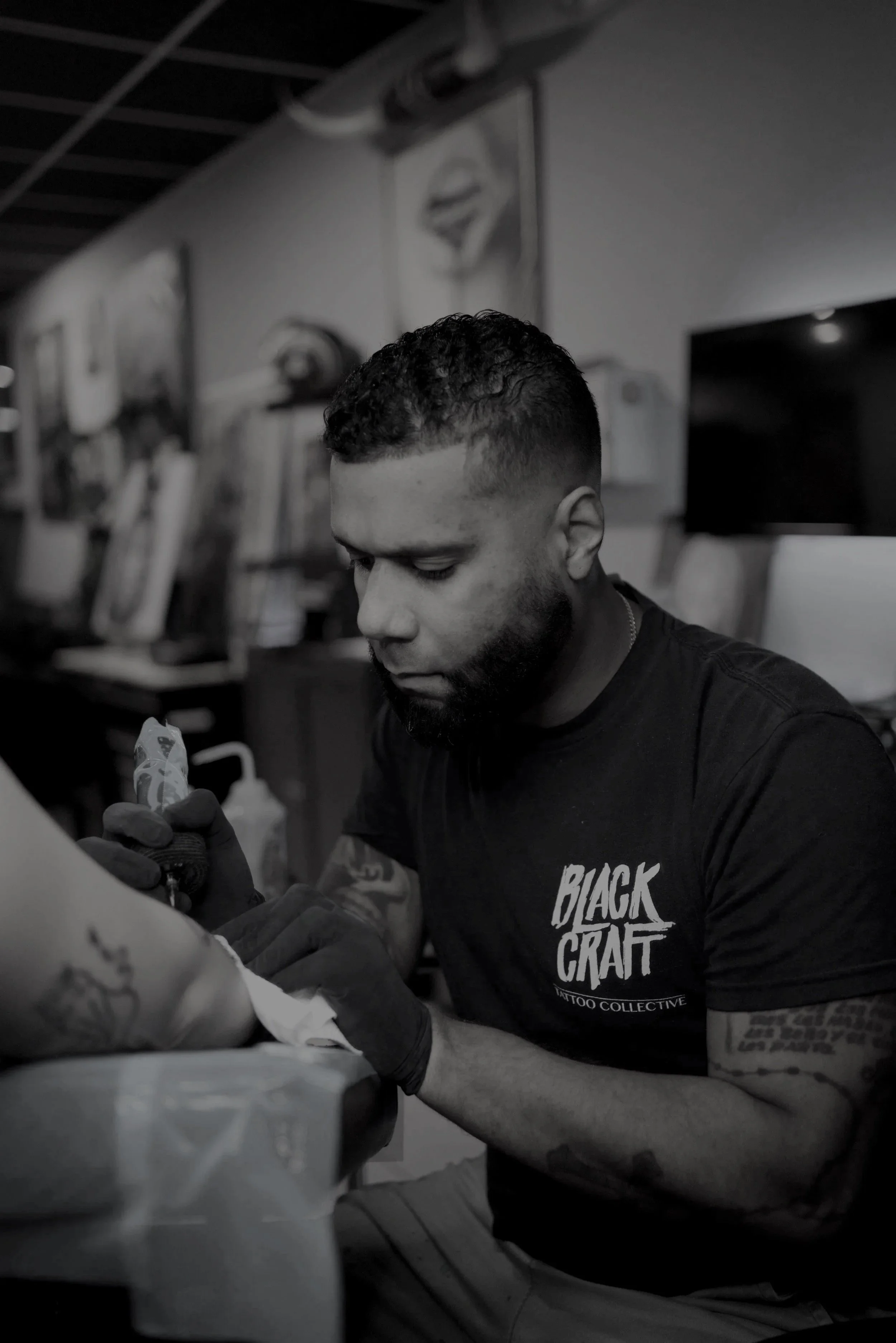 A man with a beard and tattoos getting a tattoo on his arm in a tattoo shop.