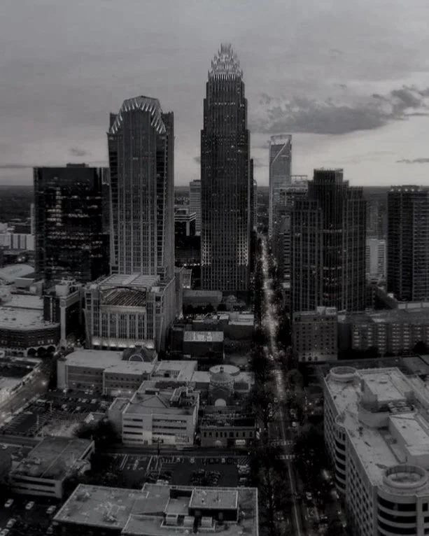 Black and white aerial view of a downtown city with tall skyscrapers and a street running through the center