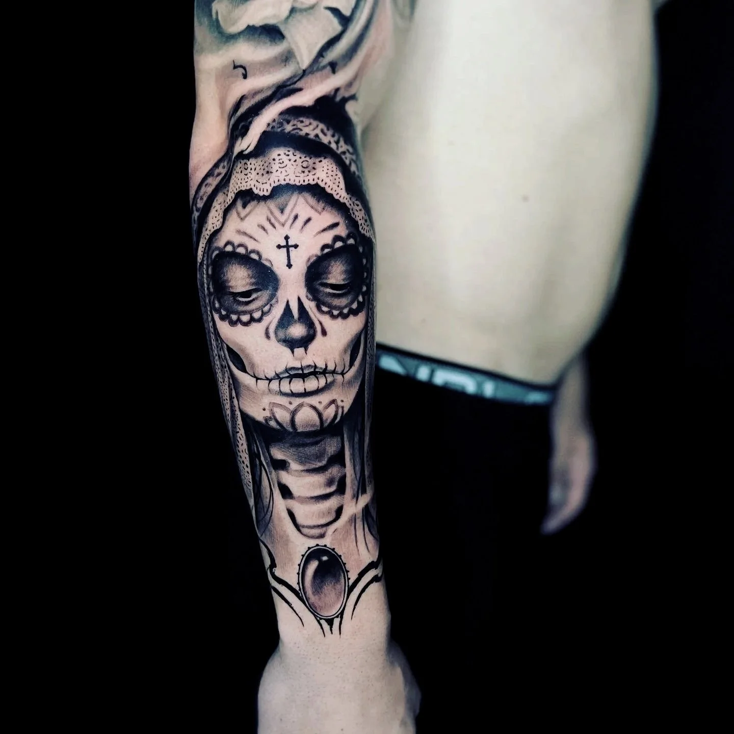 Tattoo of a sugar skull with detailed shading on a person's arm.
