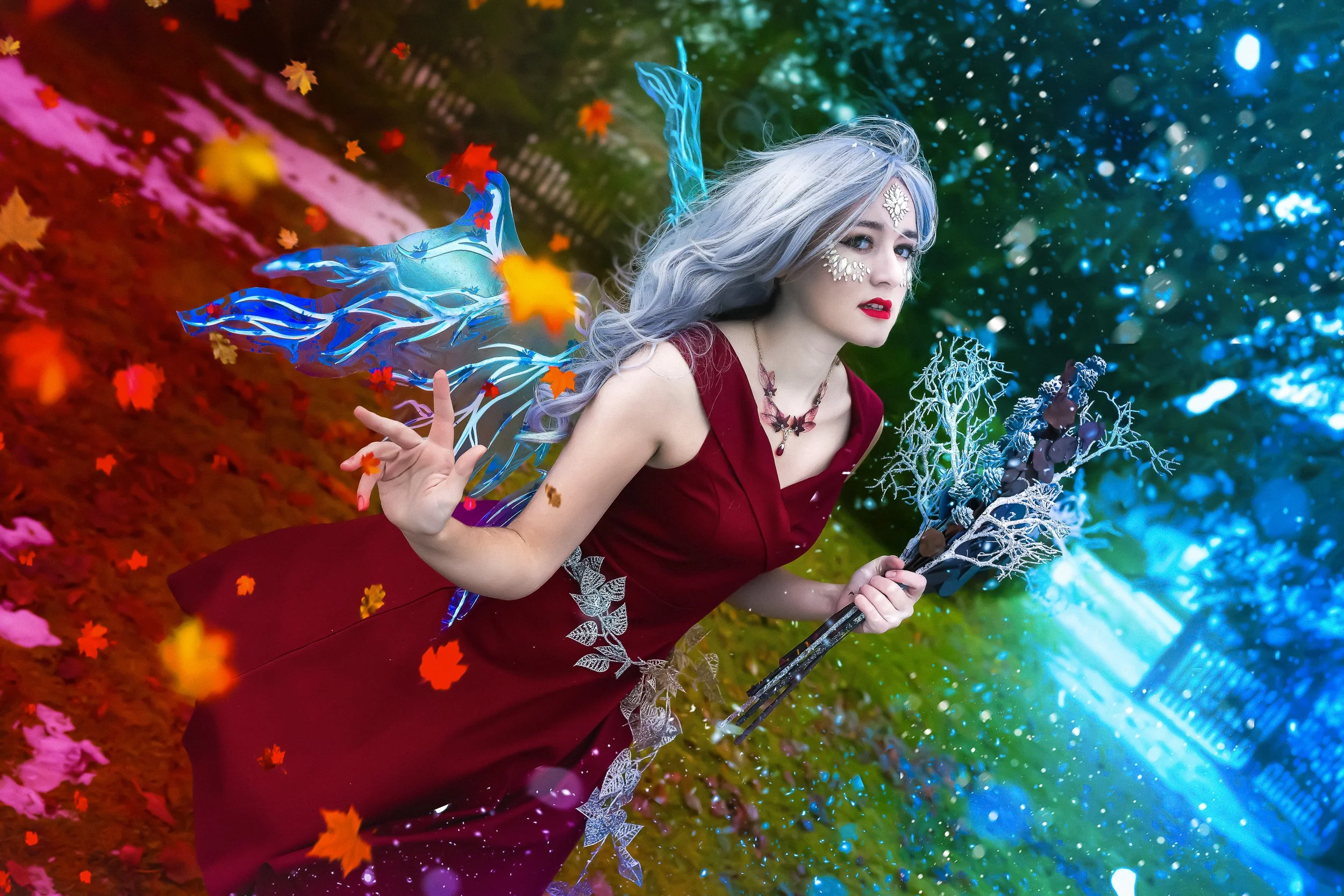 Une femme habillée en robe rouge avec des accessoires blancs et de la peinture blanche sur le visage, tenant un bâton décoratif, se tenant dans un environnement coloré avec des effets numériques et des feuilles automnales.