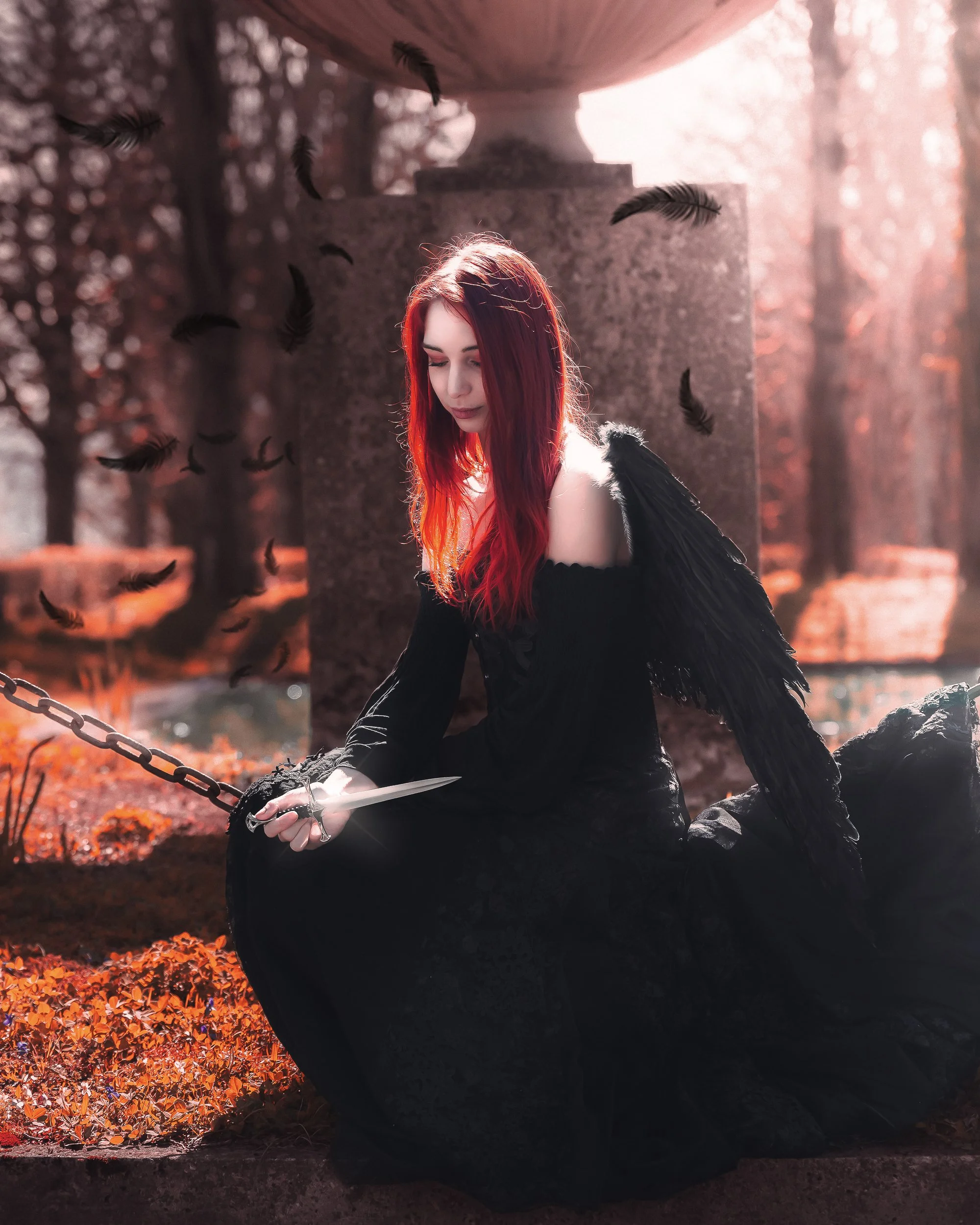 Une femme aux cheveux rouges, vêtue d'une robe noire avec des ailes noires, assise près d'une tombe dans un cimetière avec des plumes noires flottant dans l'air et un ciel en teintes chaudes.