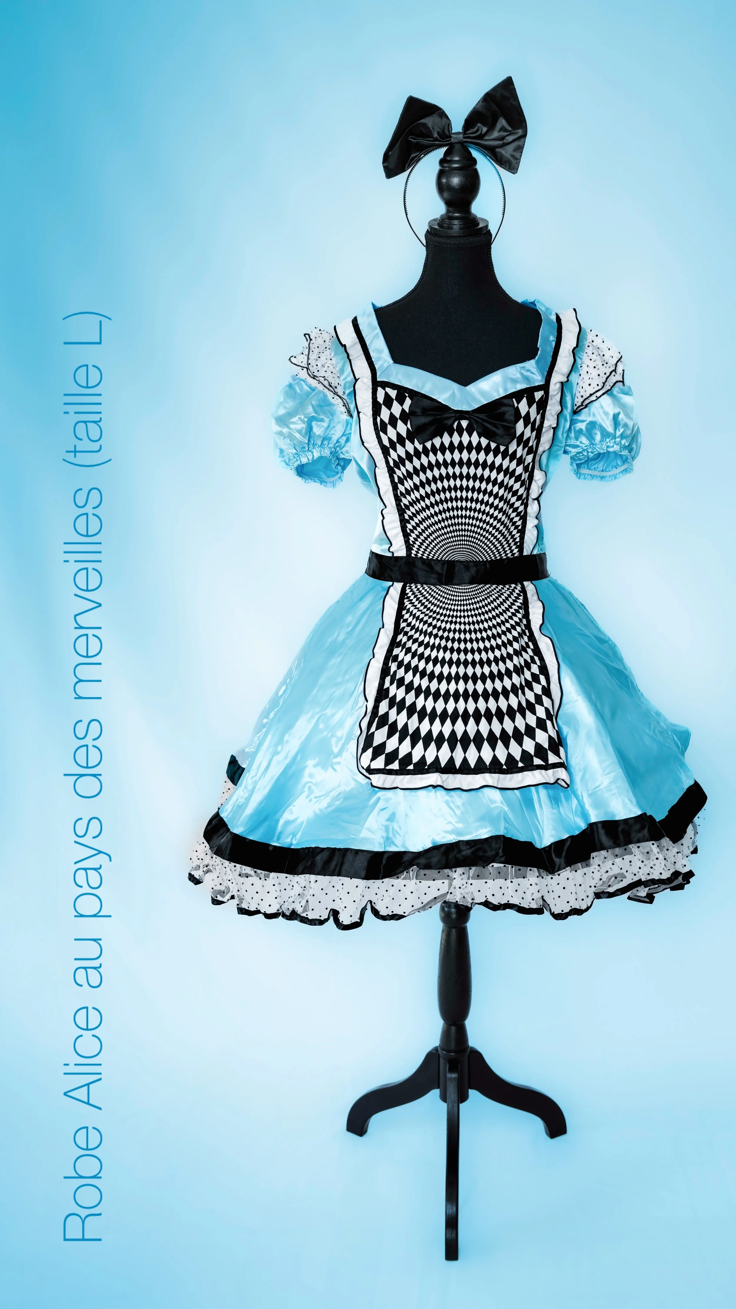 Une robe bleue de conte de fées d'Alice au pays des merveilles (taille L) affichée sur un mannequin noir contre un fond bleu clair.