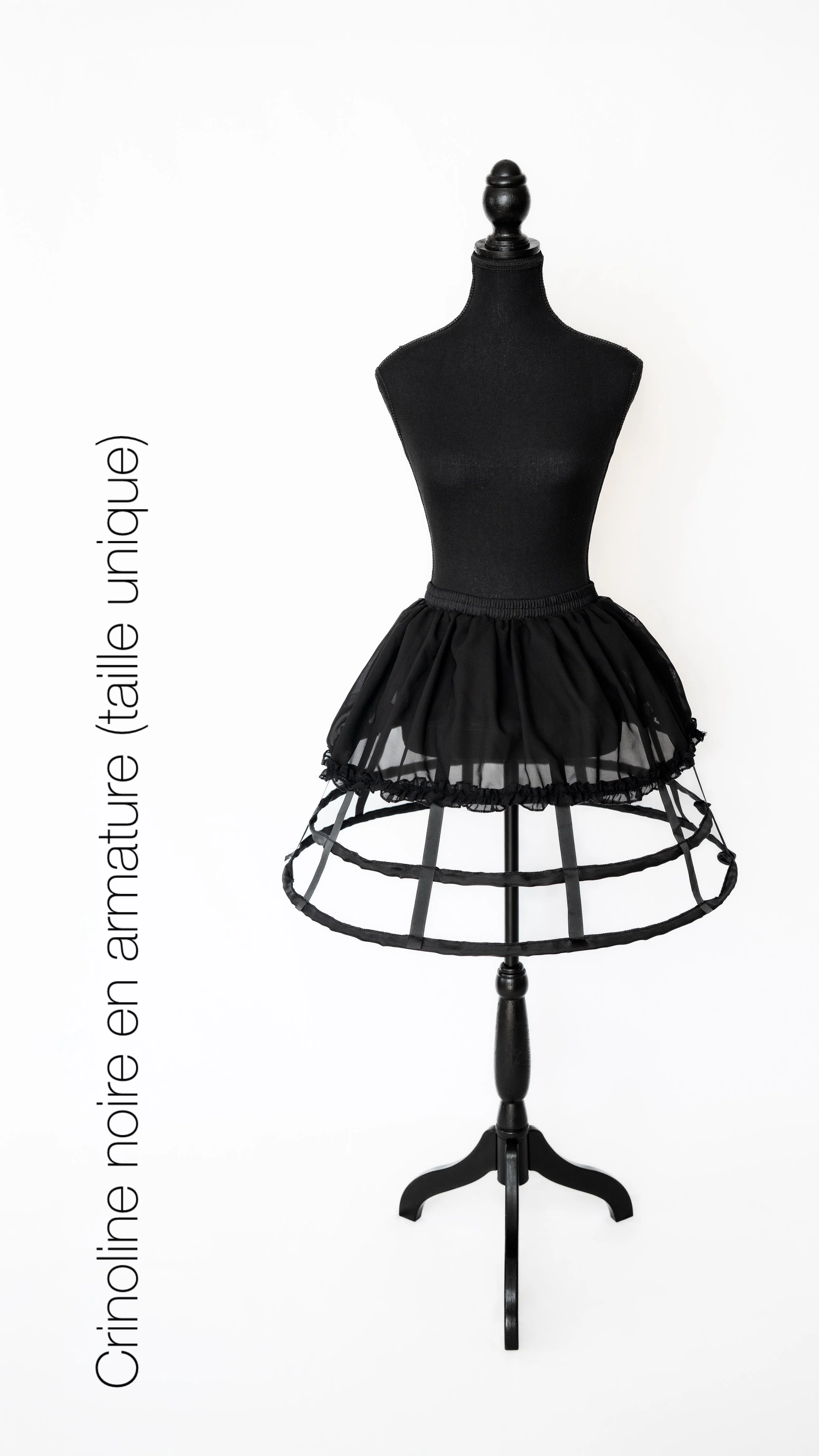 Mannequin portant une jupe noire en tulle et un haut noir sans manches, placé contre un fond blanc.