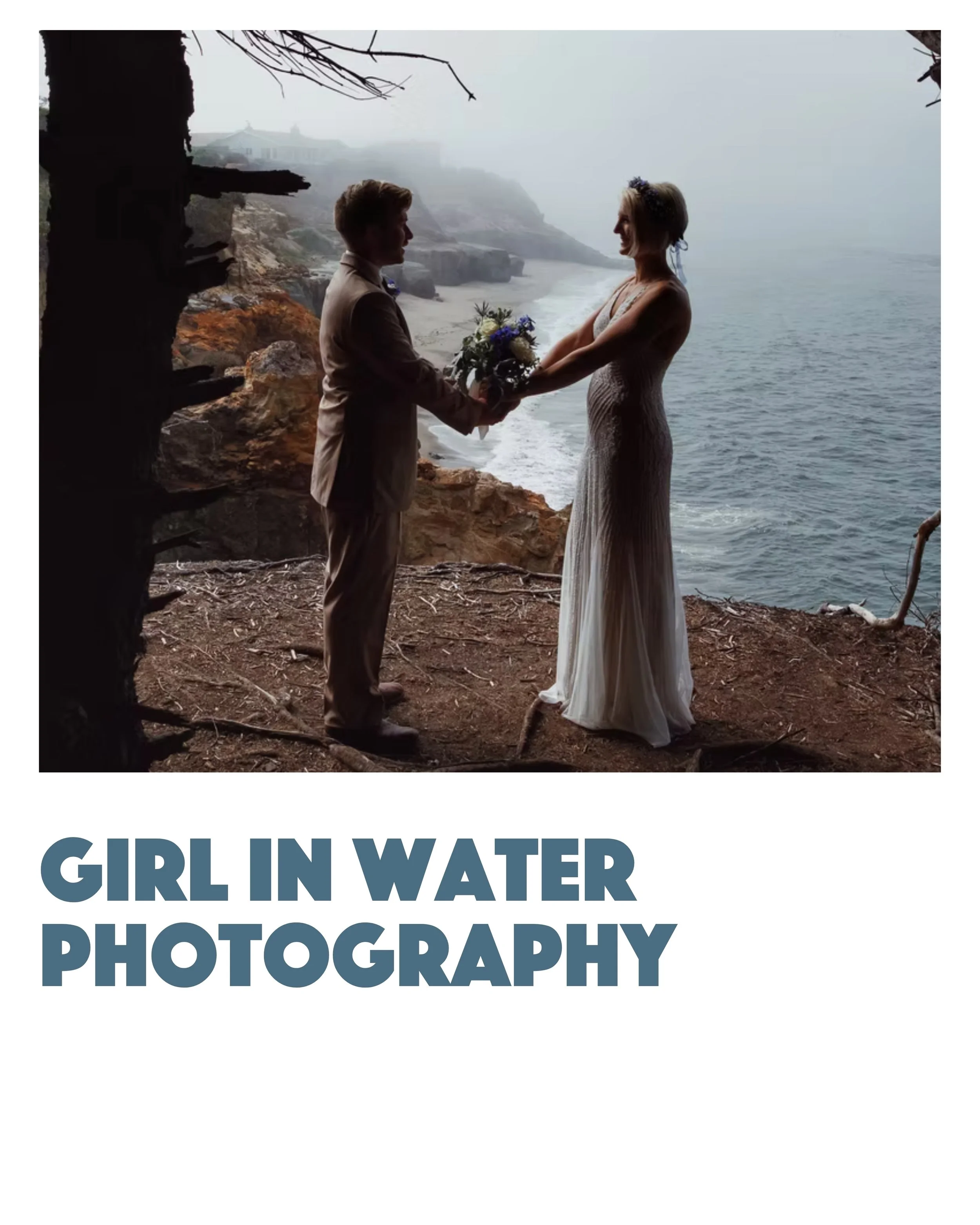 A bride and groom standing on a rocky cliff edge by the water, holding hands and looking at each other, with the bride holding a bouquet of flowers.
