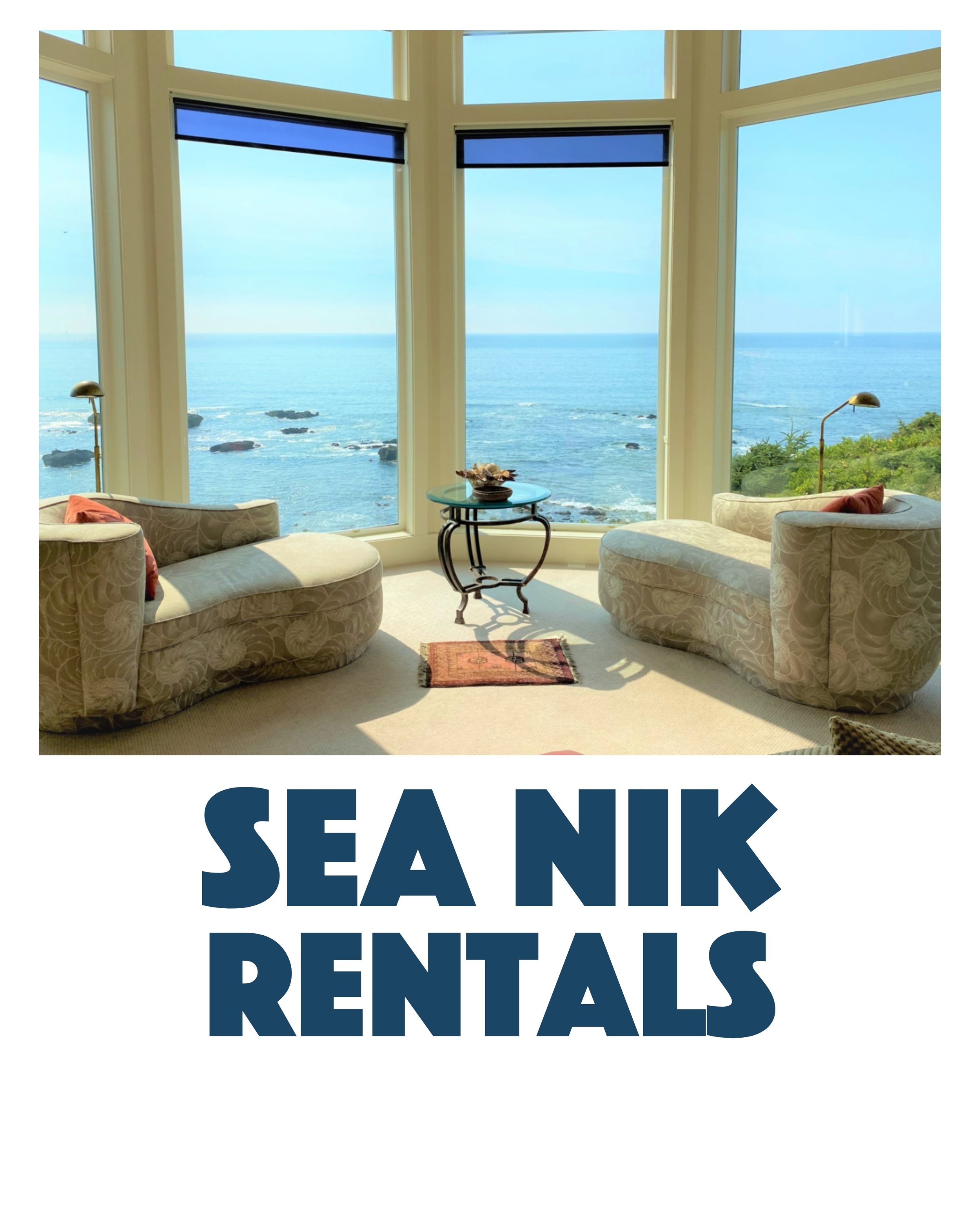 Living room with large bay windows overlooking the ocean, two curved sofas with patterned upholstery, a small round table in the center, a carpet, and two floor lamps.