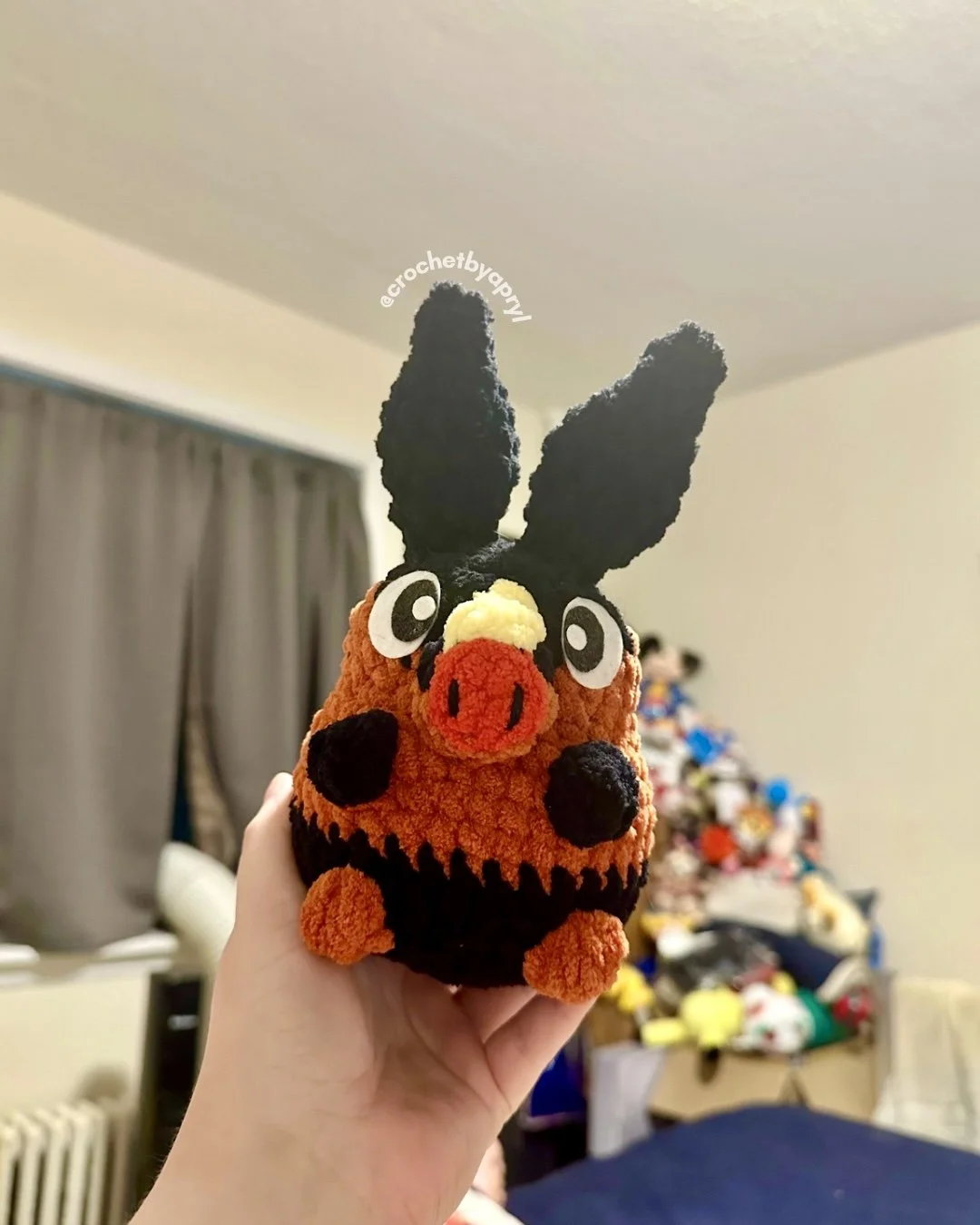 a crochet plush of tepig held by a white woman’s hand