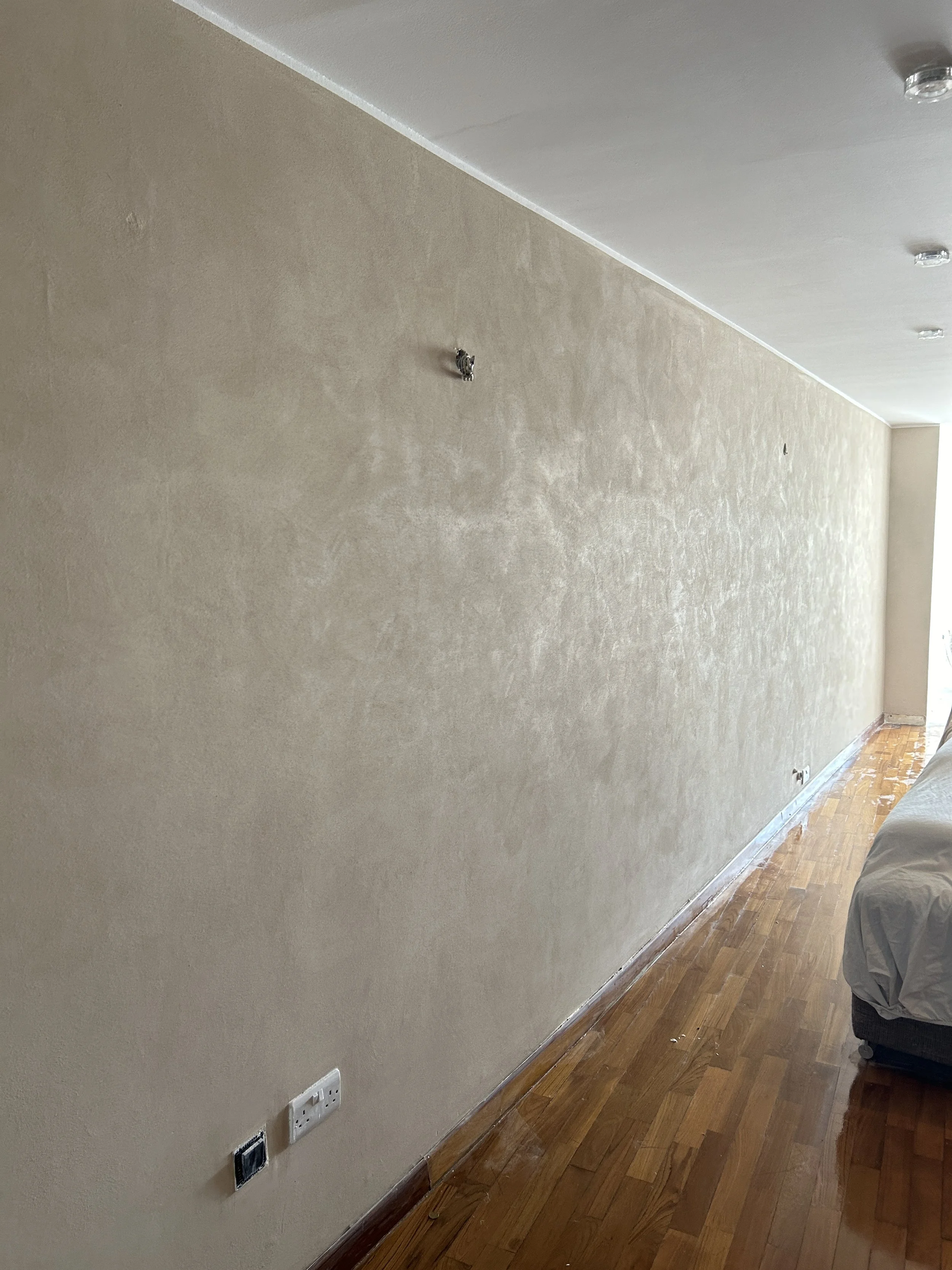 Long living room wall completed with a beige textured paint effect.