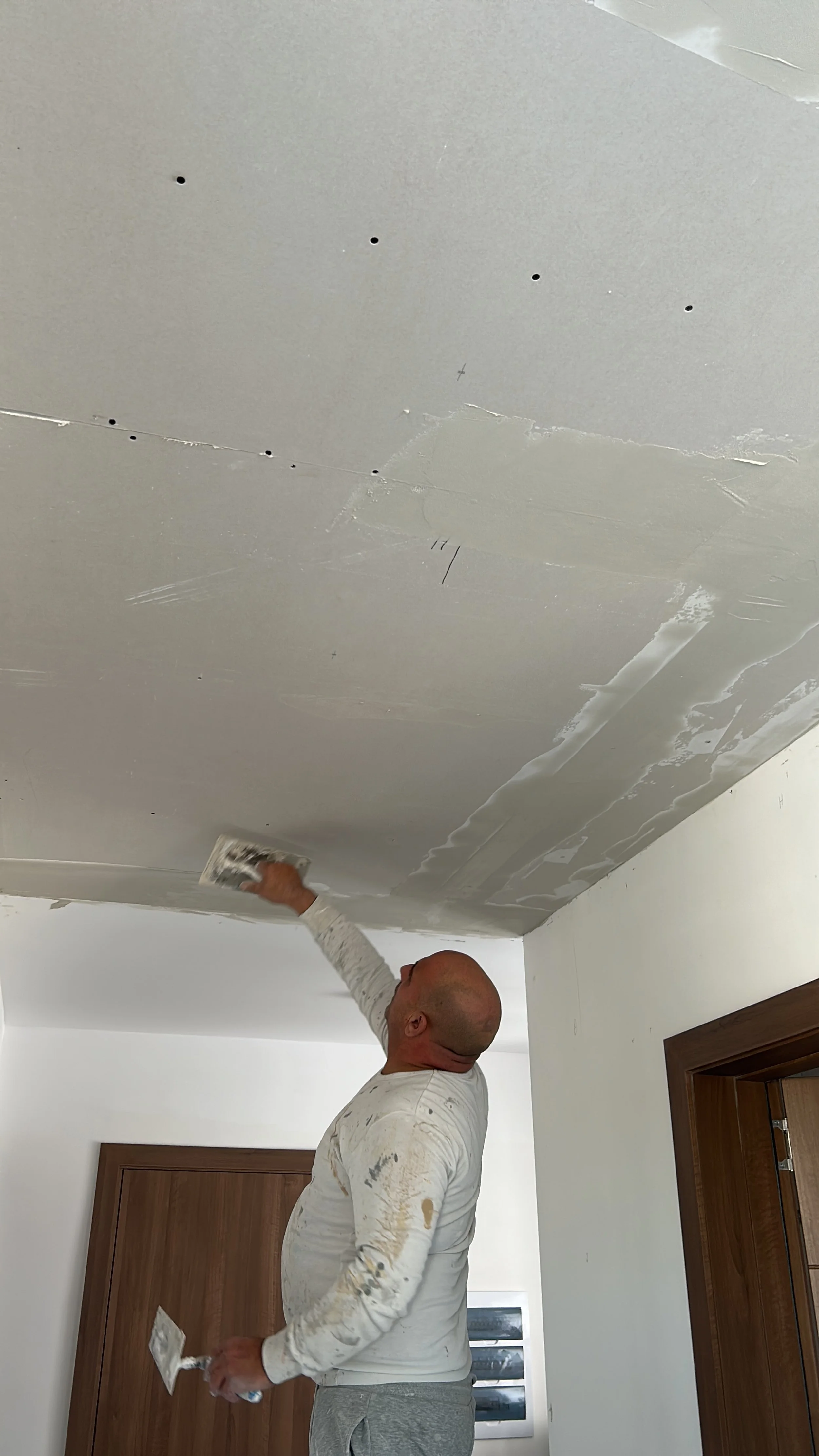 Mark working on a newly installed corridor gypsum ceiling.