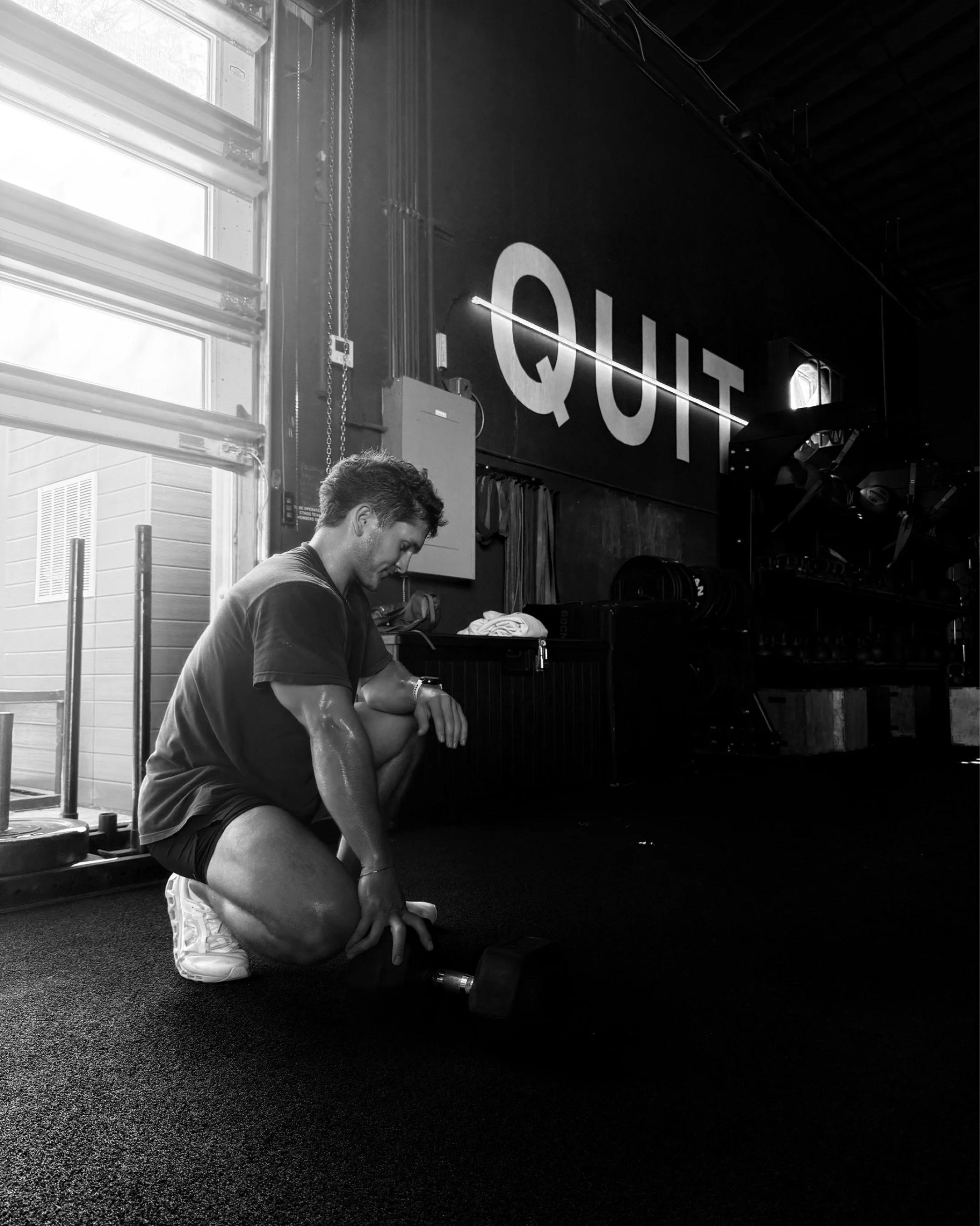 Athlete resting after a HYROX workout holding a dumbbell