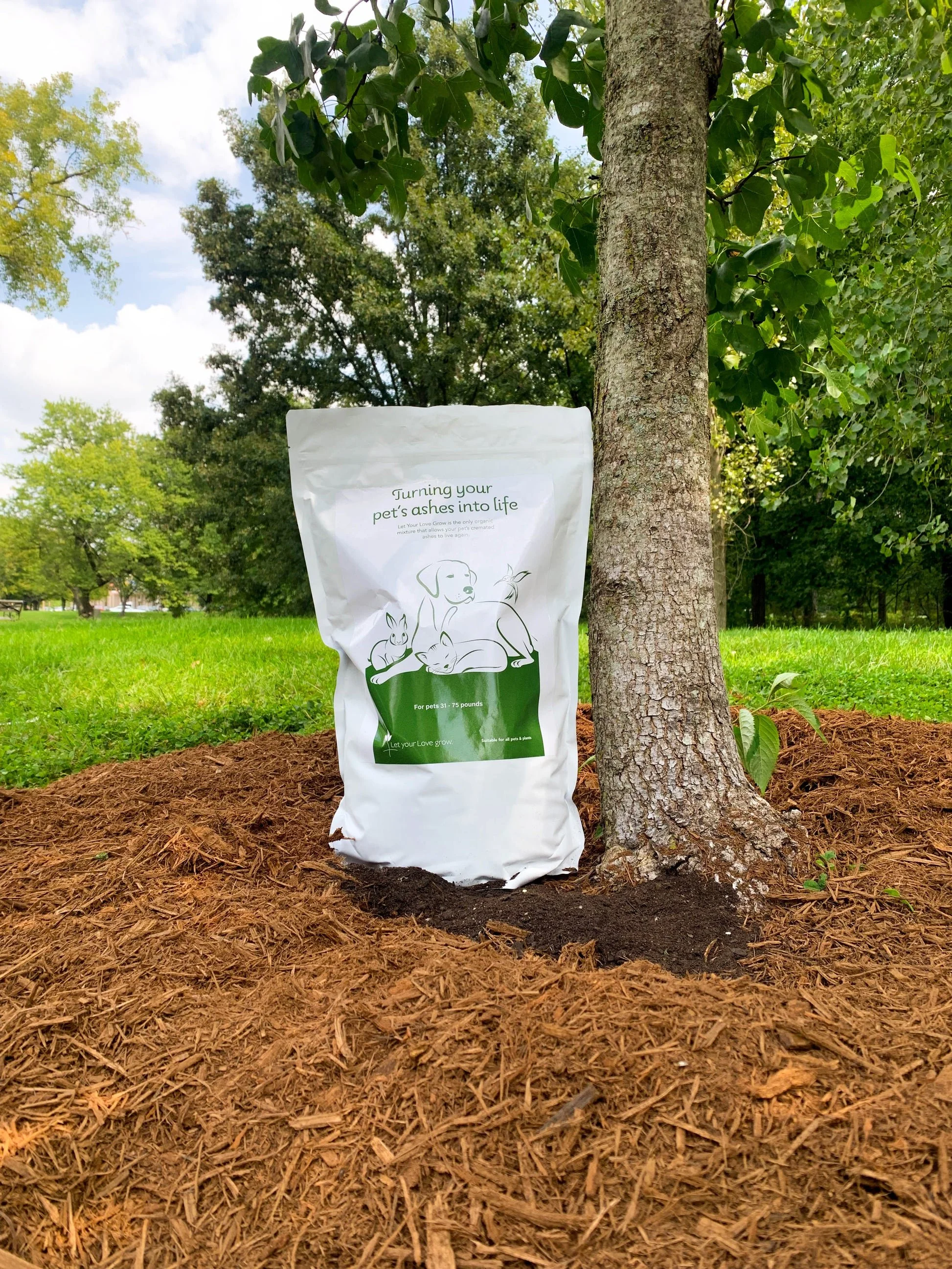 Let Your Love Grow neutralizing soil bag placed next to a tree outdoors.