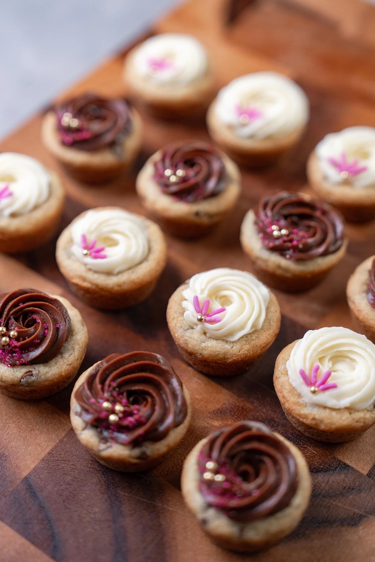 Chocolate Chip Cookie Cups with Chocolate Frosting or Cream Cheese Icing laid out on a wooden cutting board