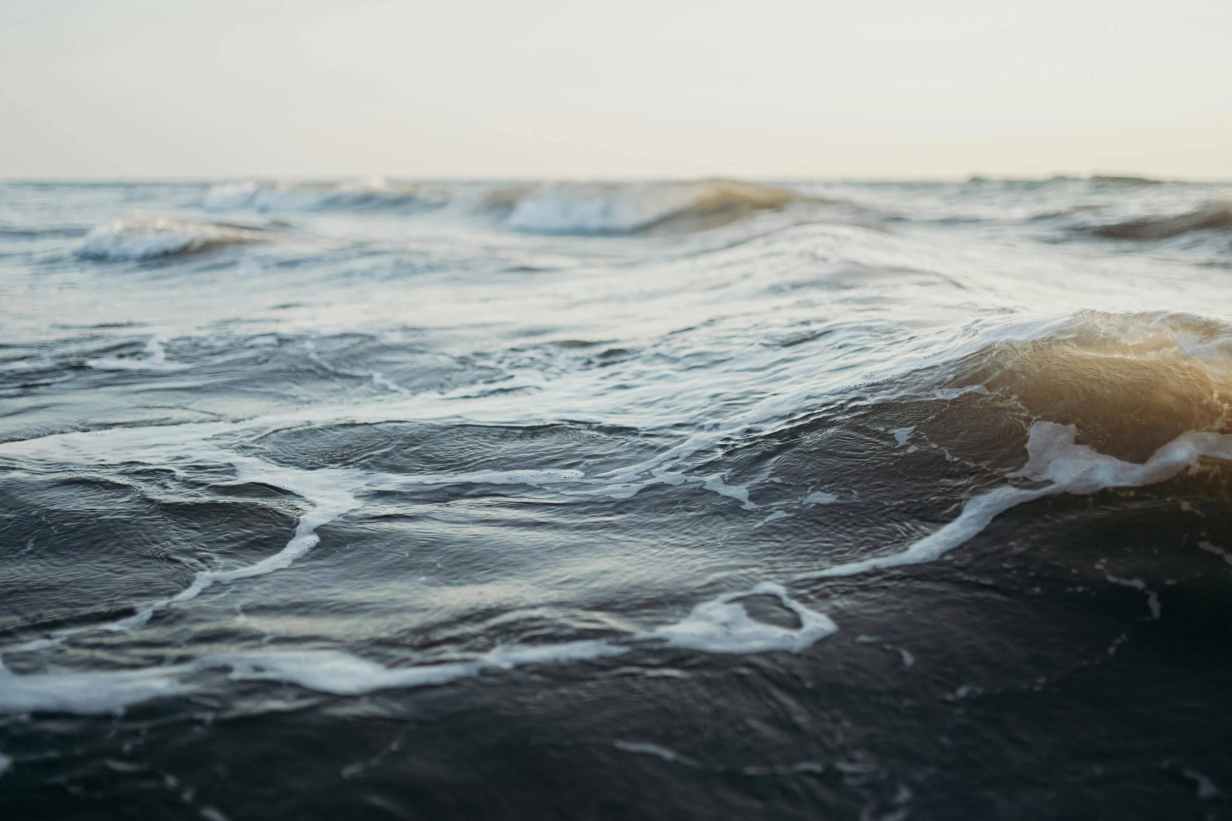 Close-up of ocean waves with foam during sunset or sunrise