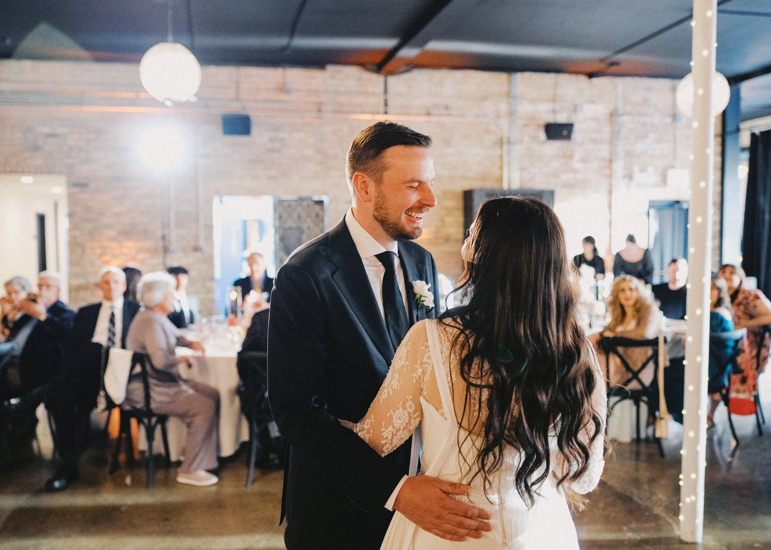Couple Dances their first dance with guests looking on