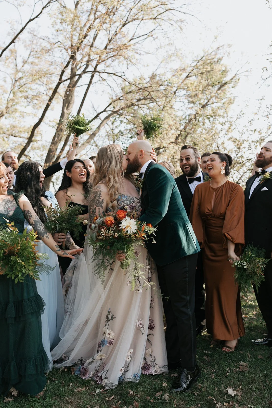 A couple kisses with their wedding party cheering on