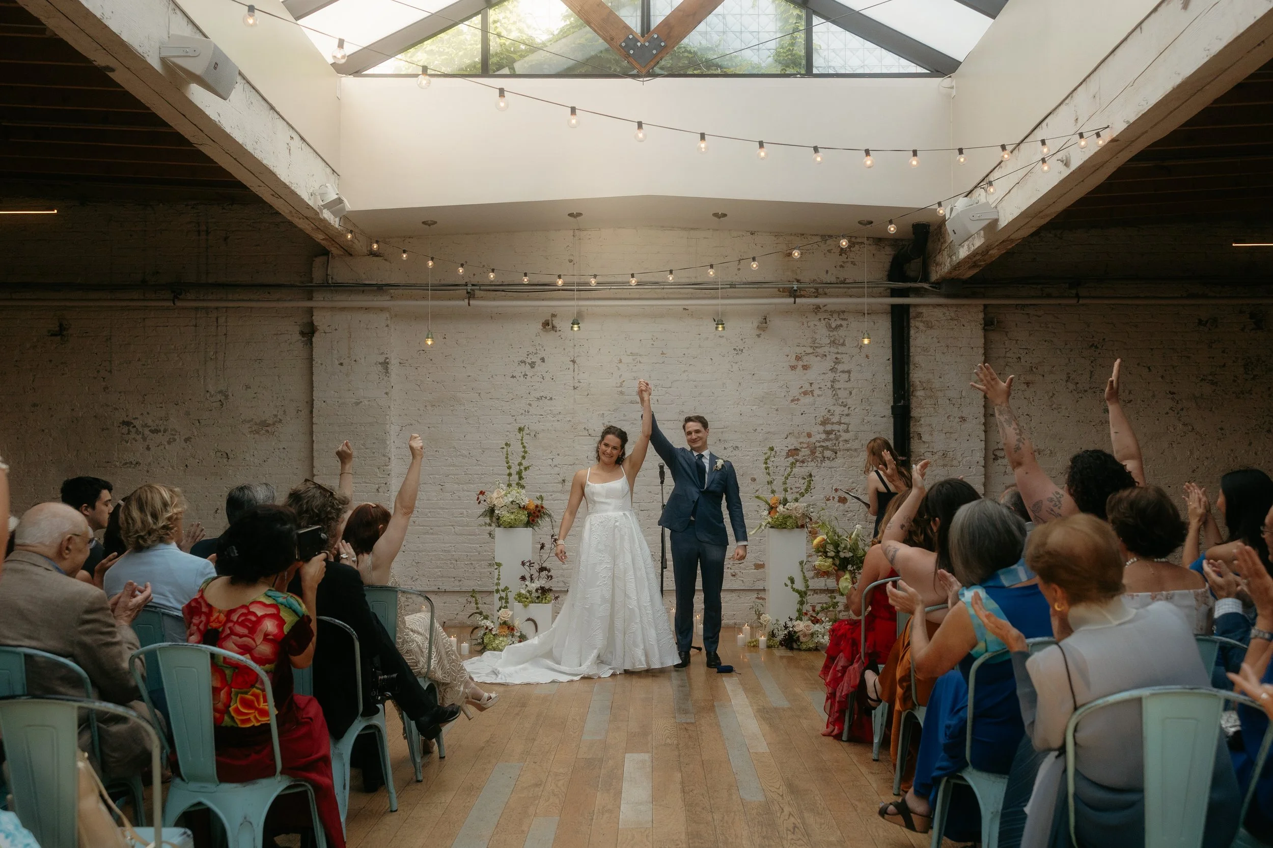 A couple excited raises their hands together following their wedding pronouncement