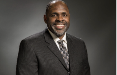 A smiling man in a suit and tie posing for a professional headshot.