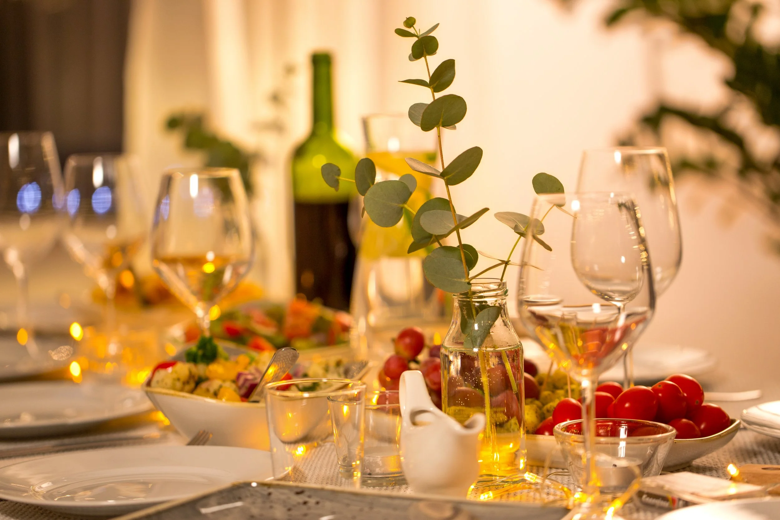 Koreanna Kitchen elegant table setting with wine glasses, greenery and warm ambient lighting