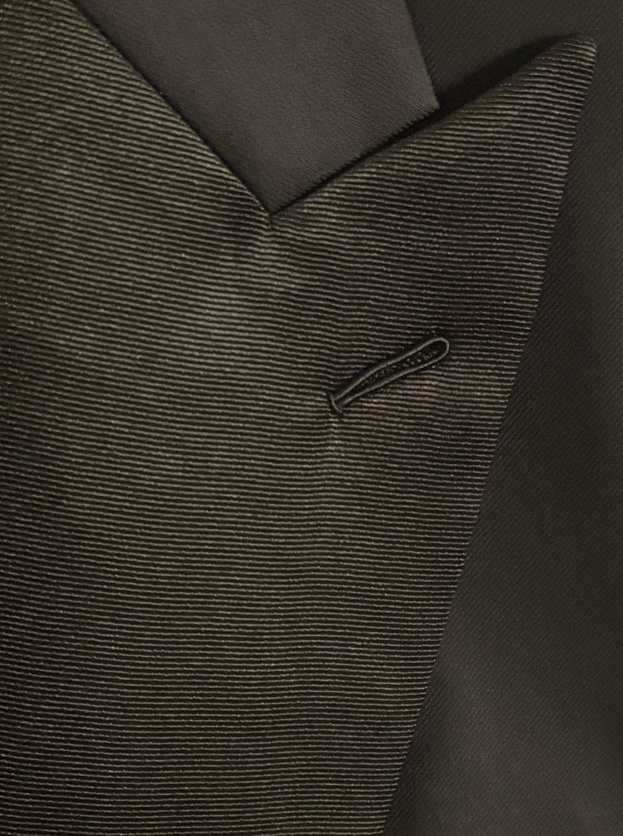 A close-up of a custom made black silk grosgrain tuxedo peak lapel with a Milanese buttonhole.