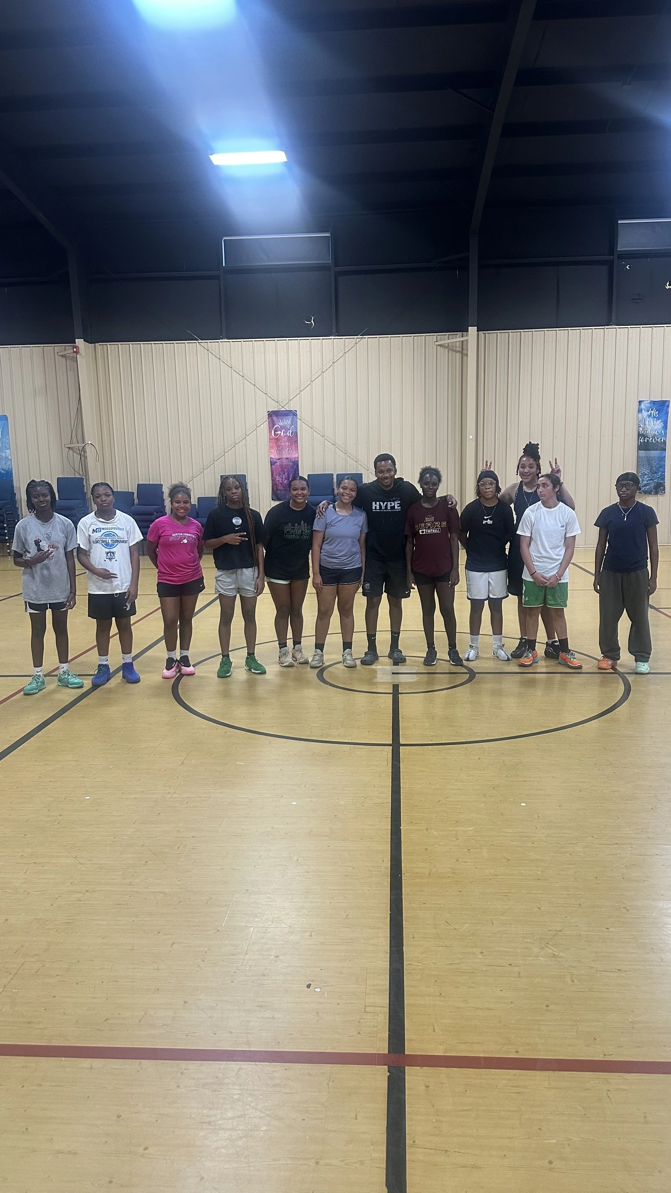 Scenic landscape of a large lake surrounded by rolling hills and towering mountains in the background with cloudy sky.