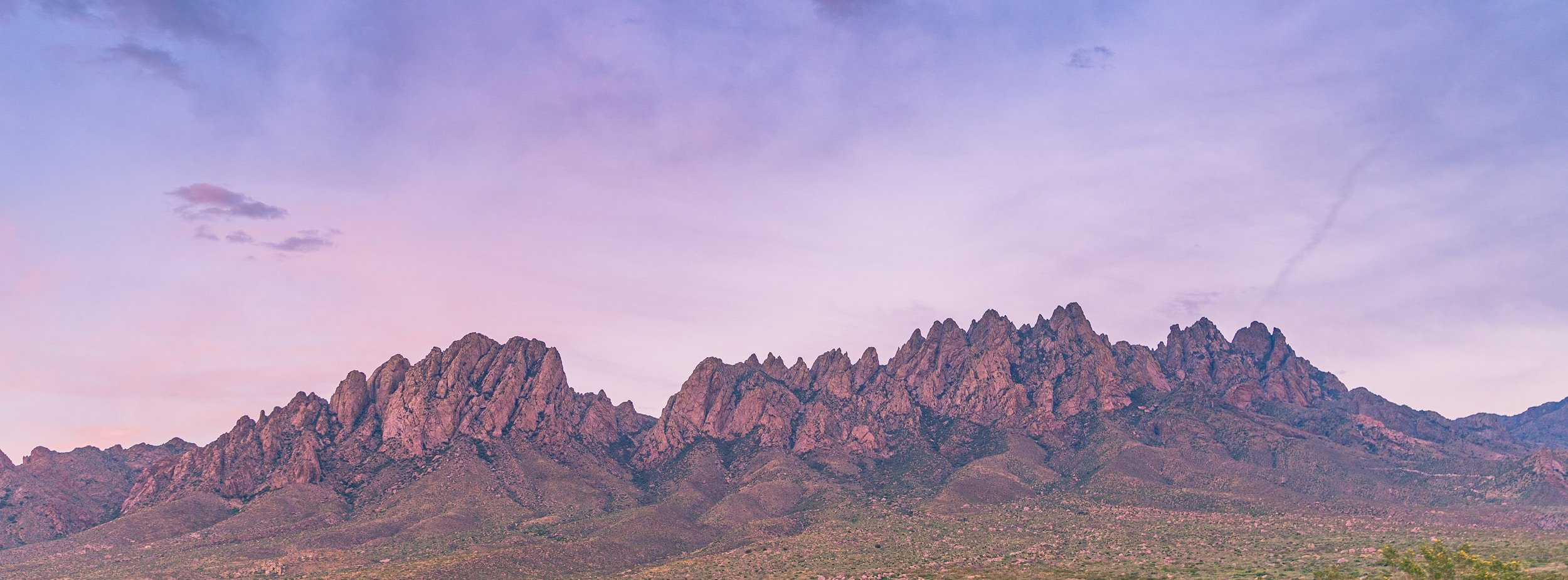 Mountain range during early evening with purple and pink hues in the sky.