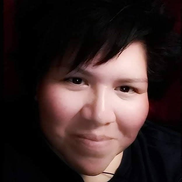 Close-up of a person with short dark hair smiling at the camera.