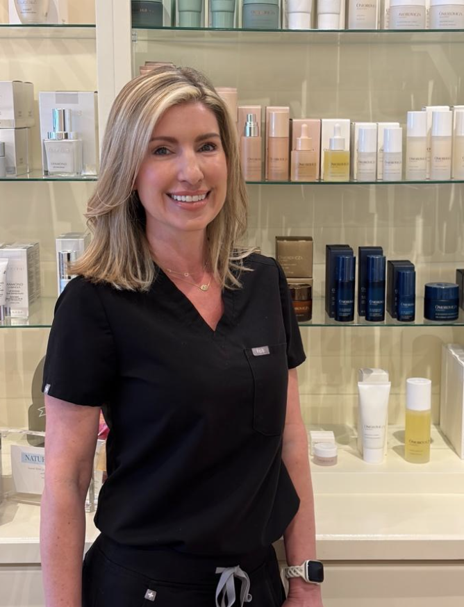 Image of a blonde woman in scrubs smiling at the camera.