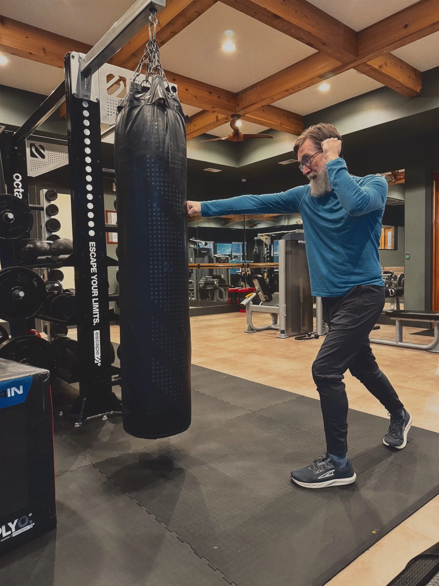 Tim Earley in an indoor gym punching a heavy bag for boxing with his fist.