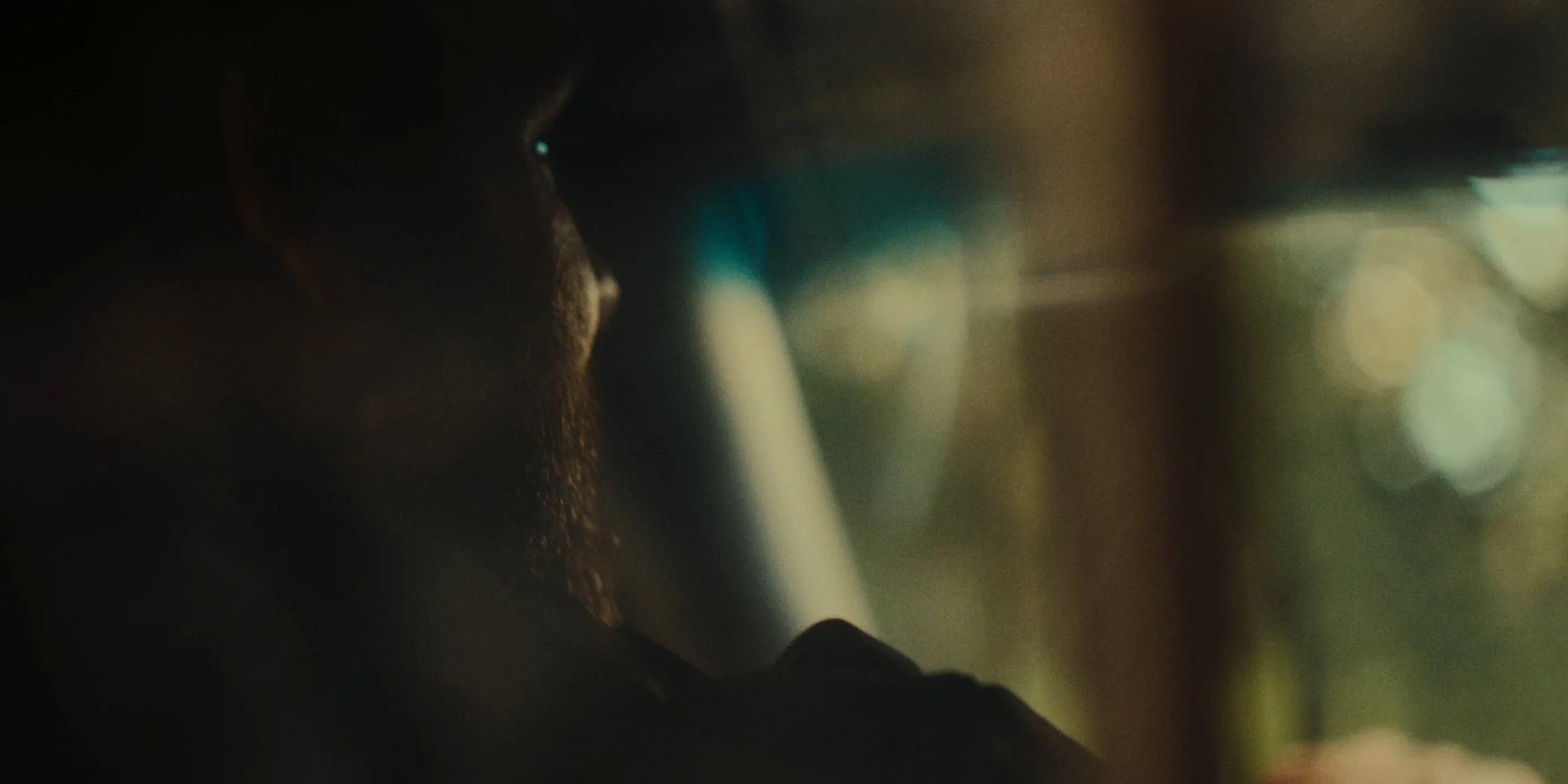 Close-up of a person's face at night, with a beard, looking at their phone in a dimly lit environment.