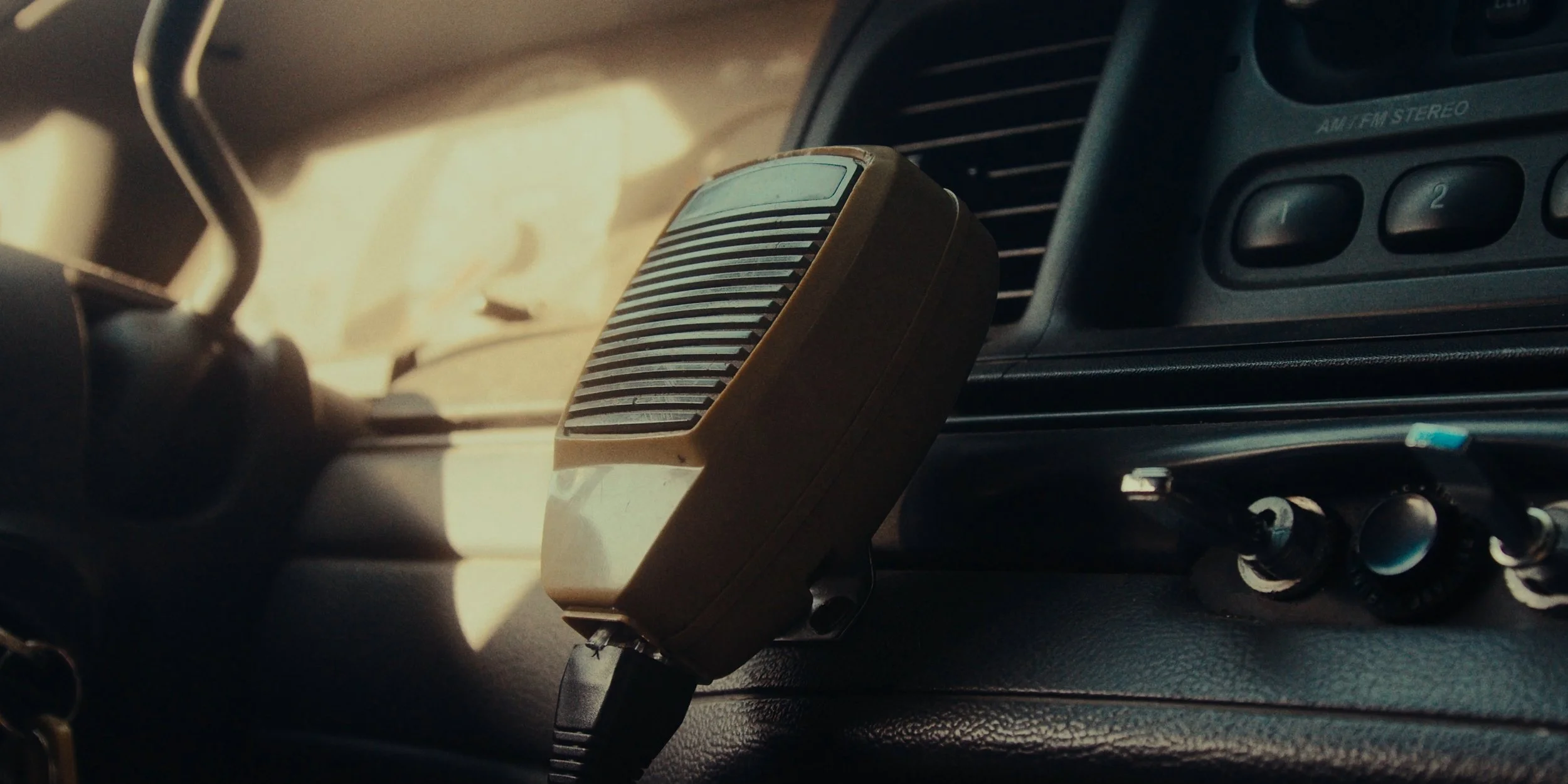 An old air purifier attached to a car dashboard with a strip of sunlight illuminating it.