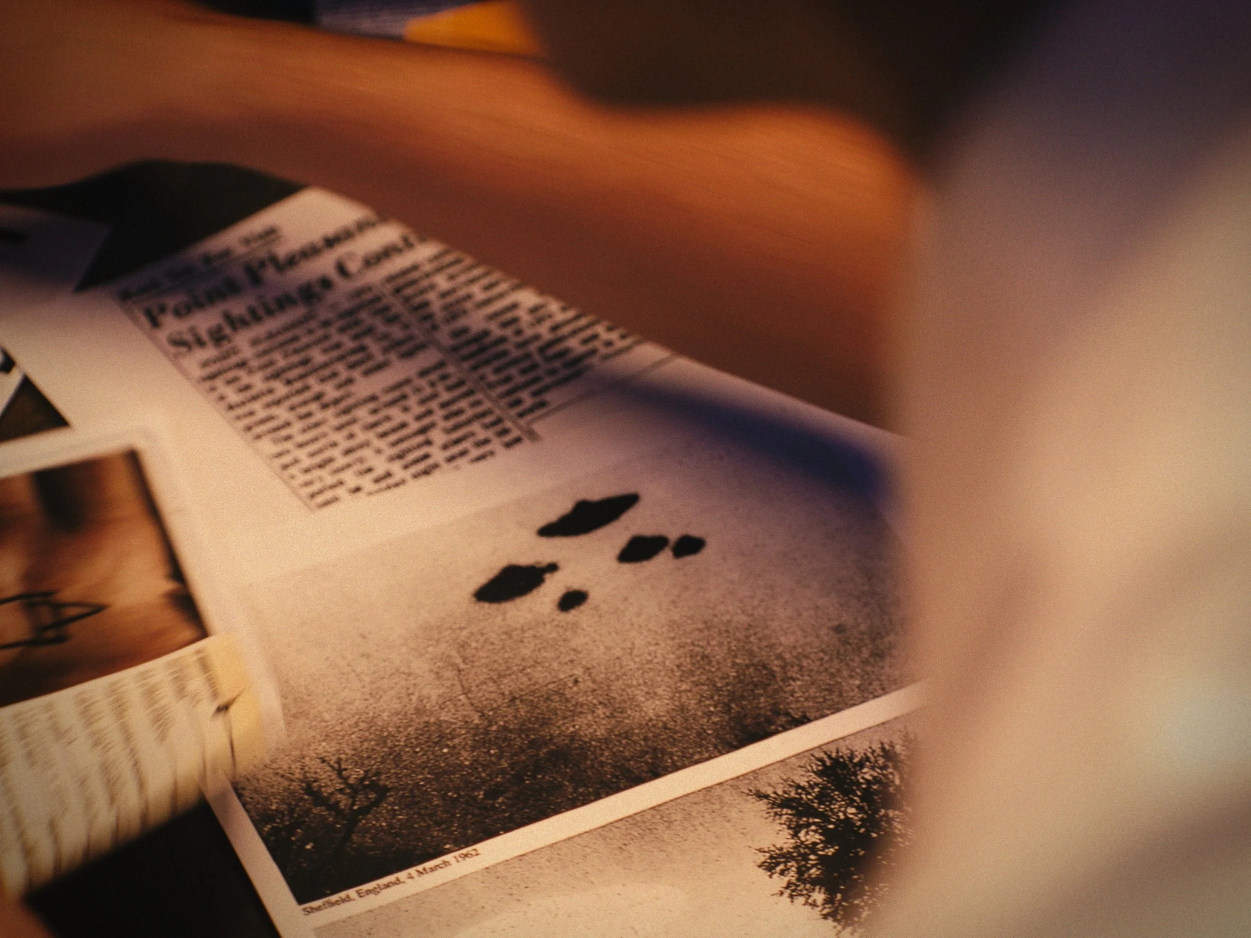 A newspaper open to a page with an article about a flash flood in Sheffield, England, dated March 4, 1982, with a photograph showing water puddles and a tree.