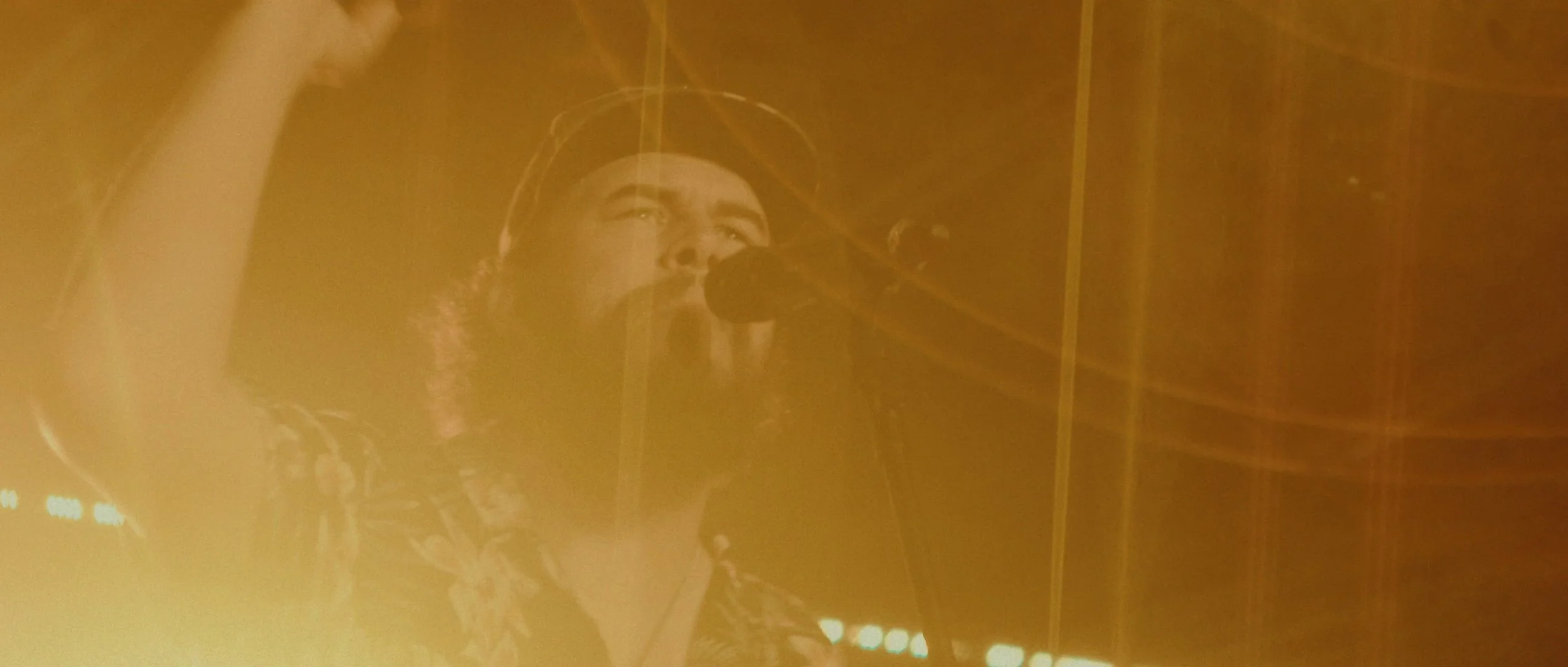 A woman singing into a microphone during a performance, with warm, dim lighting.