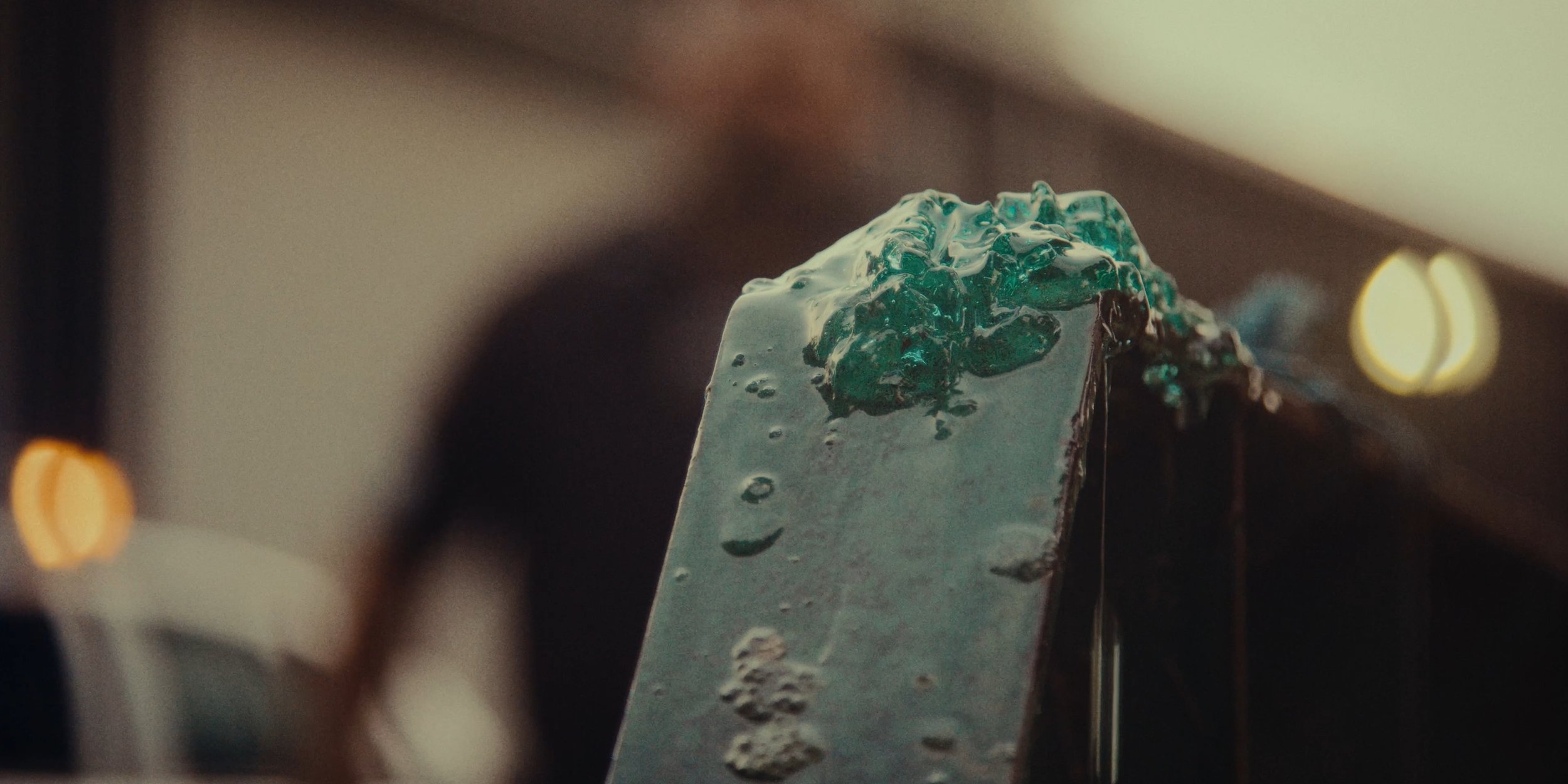 Close-up of a metal casting mold with molten metal pouring into it, with blurred background lighting.