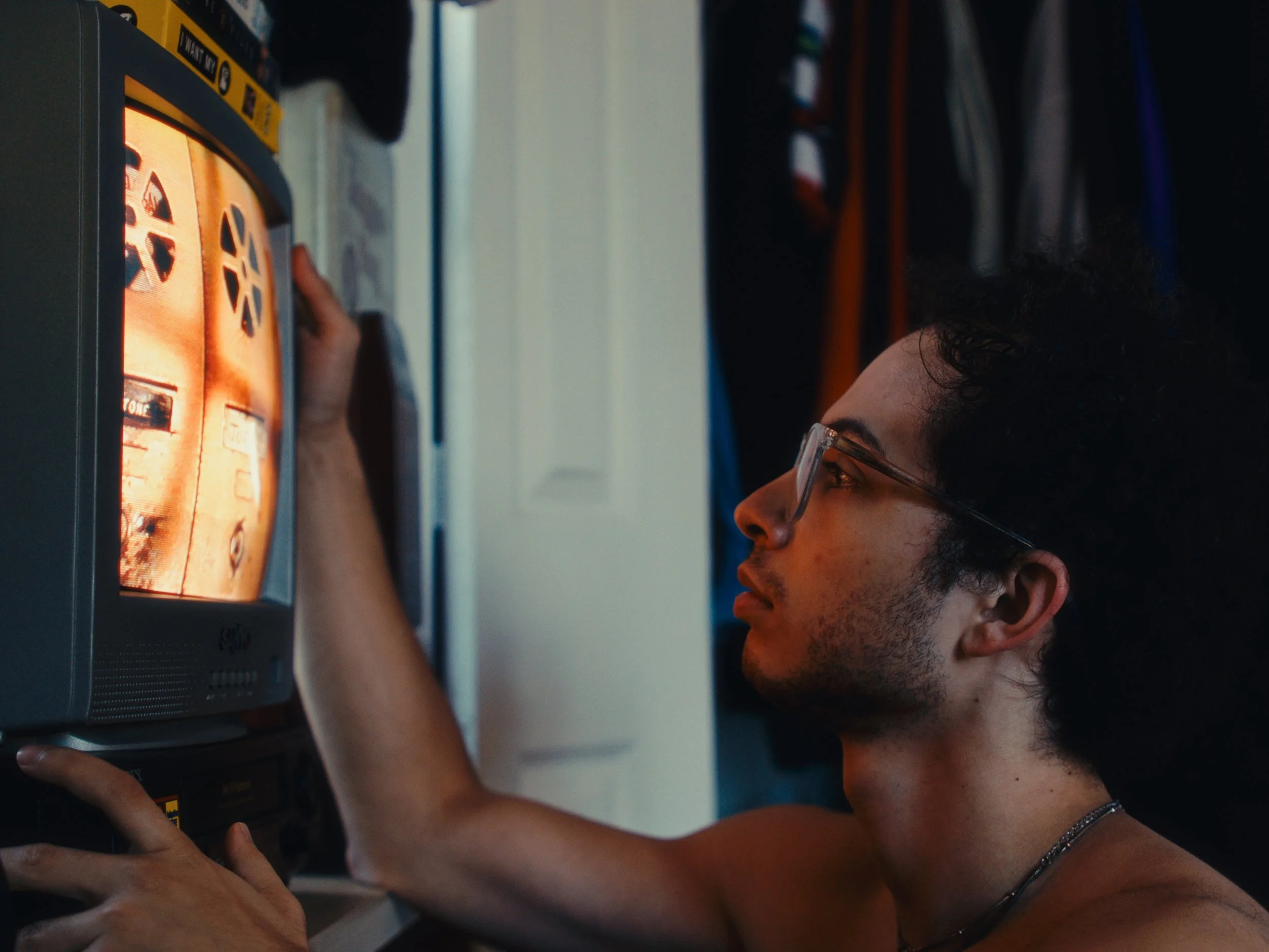 A young person with glasses and curly hair playing a vintage video game console with a small screen. Vintage 1980's