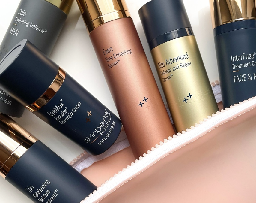 Collection of skincare bottles inside a pink bag, including products like Overnight Cream, Serum, Defense and Repair, and Moisturizer