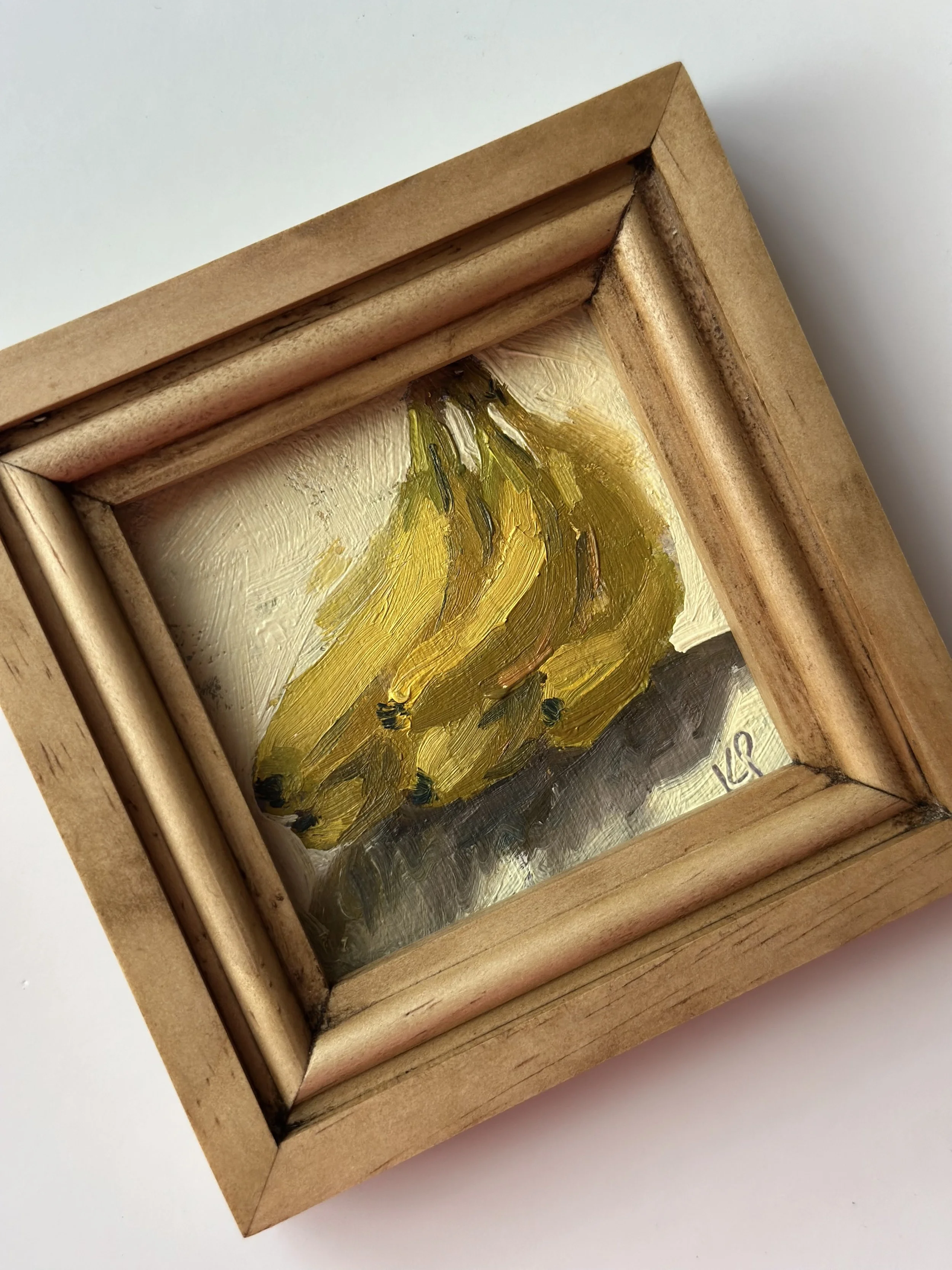 Small painting of bananas in a wooden frame.