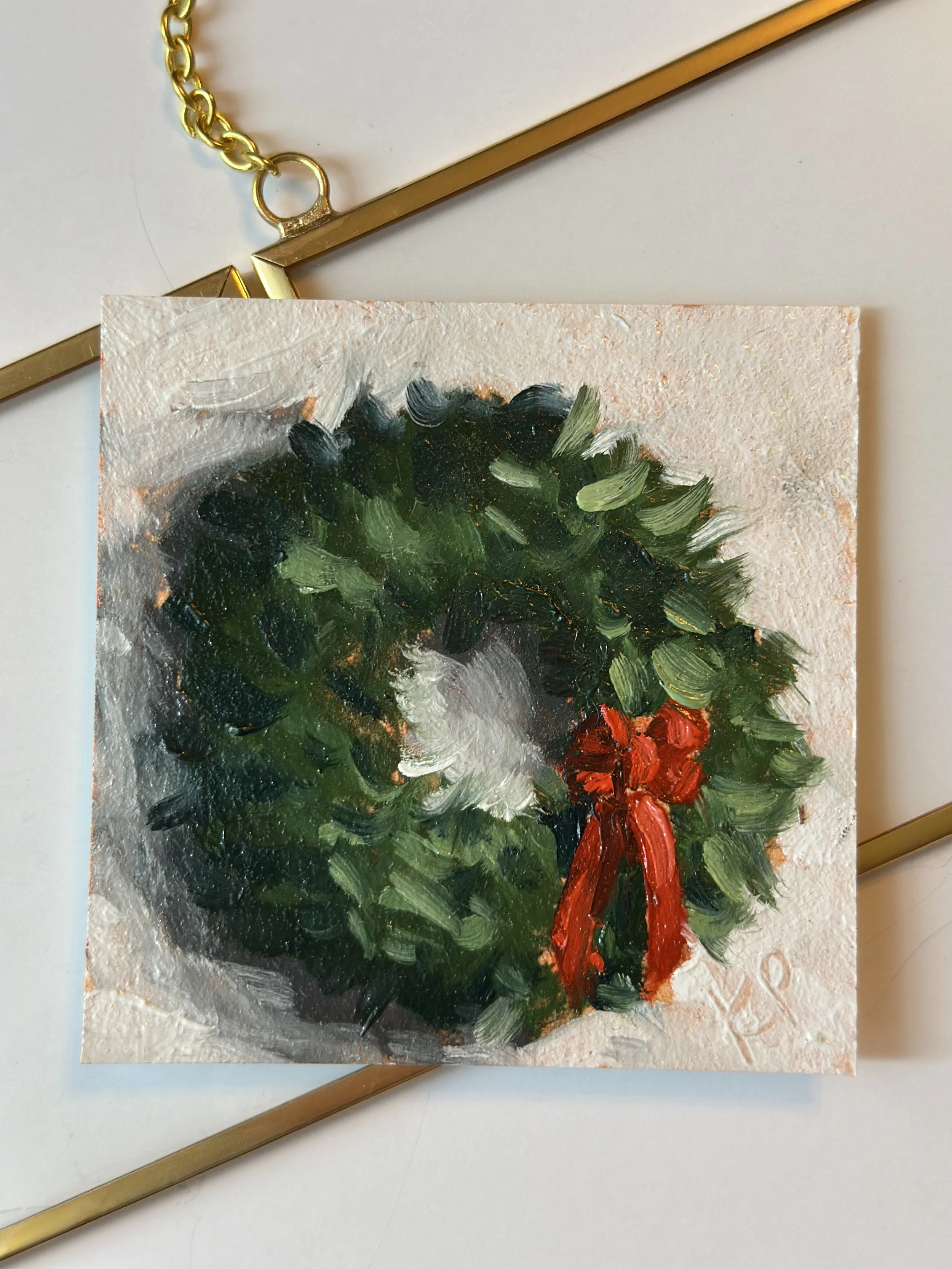 Painted Christmas wreath with green leaves, red bow, and white background, hanging on a gold bar.