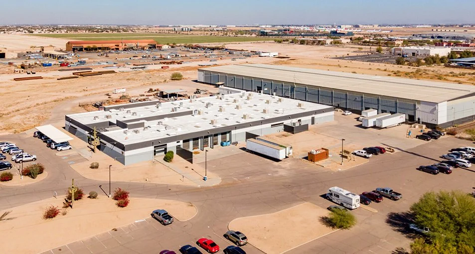 Large industrial warehouse with parking lot and trucks in a desert area